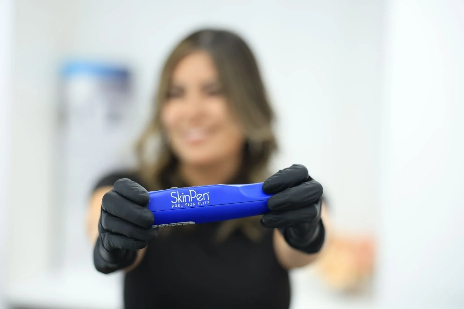 Esthetician holding SkinPen Precision Elite device, offering professional skin rejuvenation treatments for smoother texture and tone.