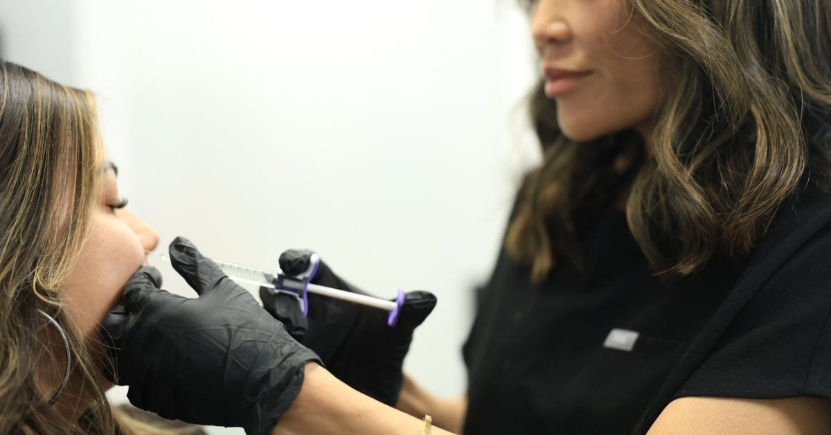 Aesthetic injector in Hawaii in black gloves performing a cheek filler treatment on a client in a bright clinic.