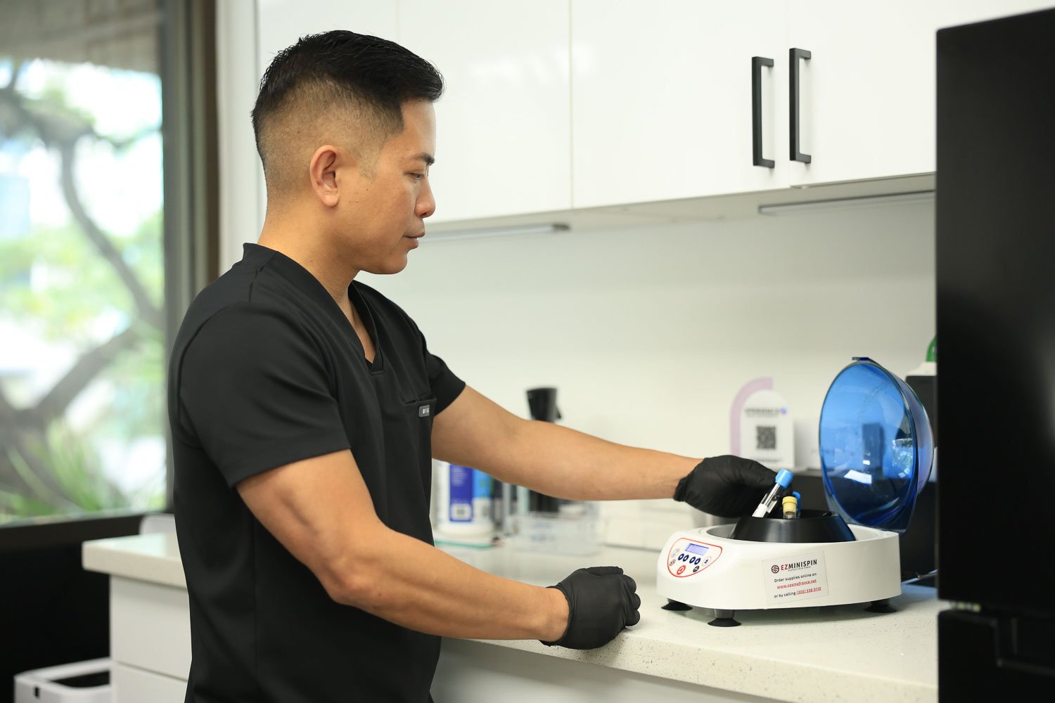 Aesthetic provider in scrubs preparing PRF injections using centrifuge machine at Impeccable Aesthetics med spa Honolulu.