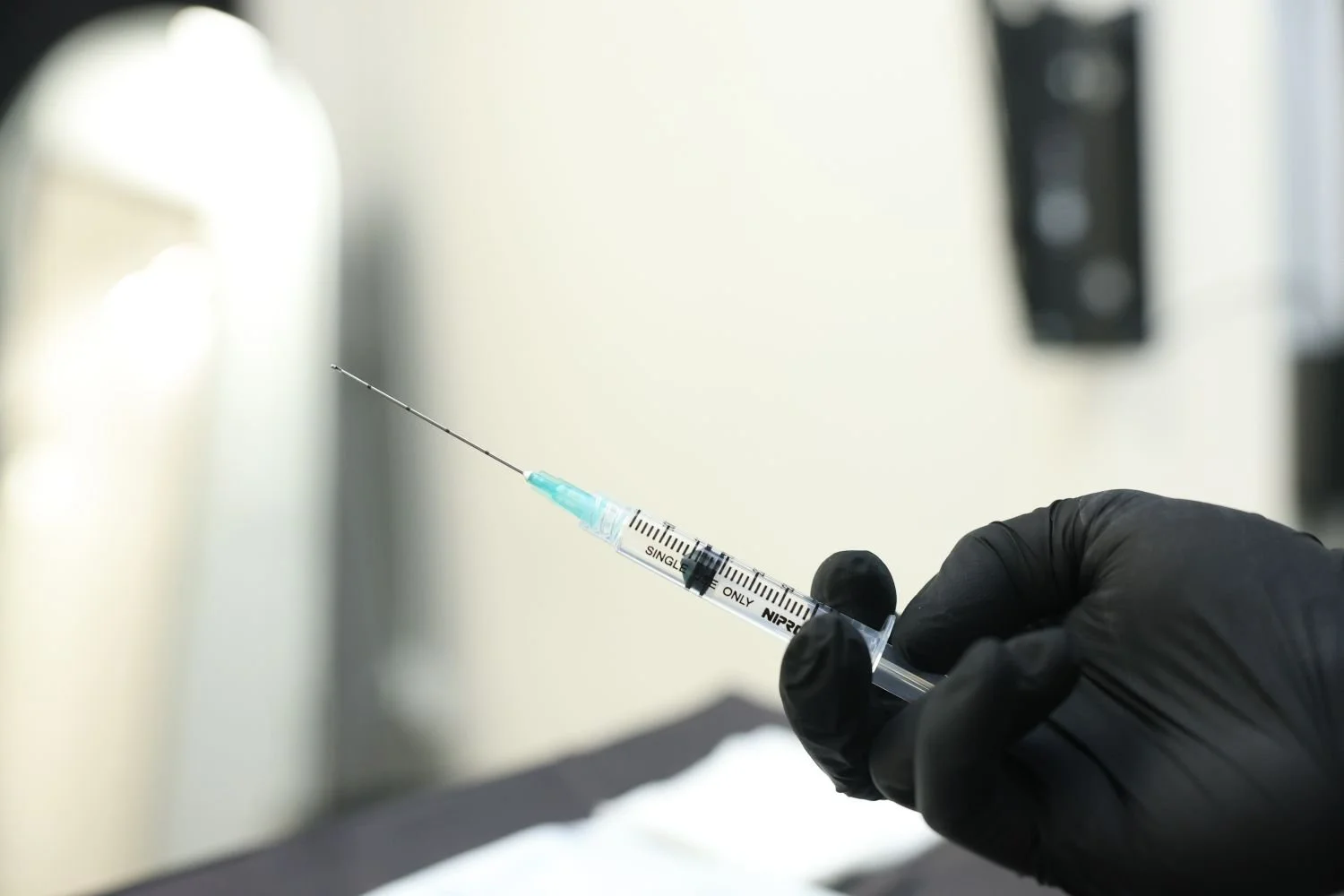 A gloved hand holding an injection needle.