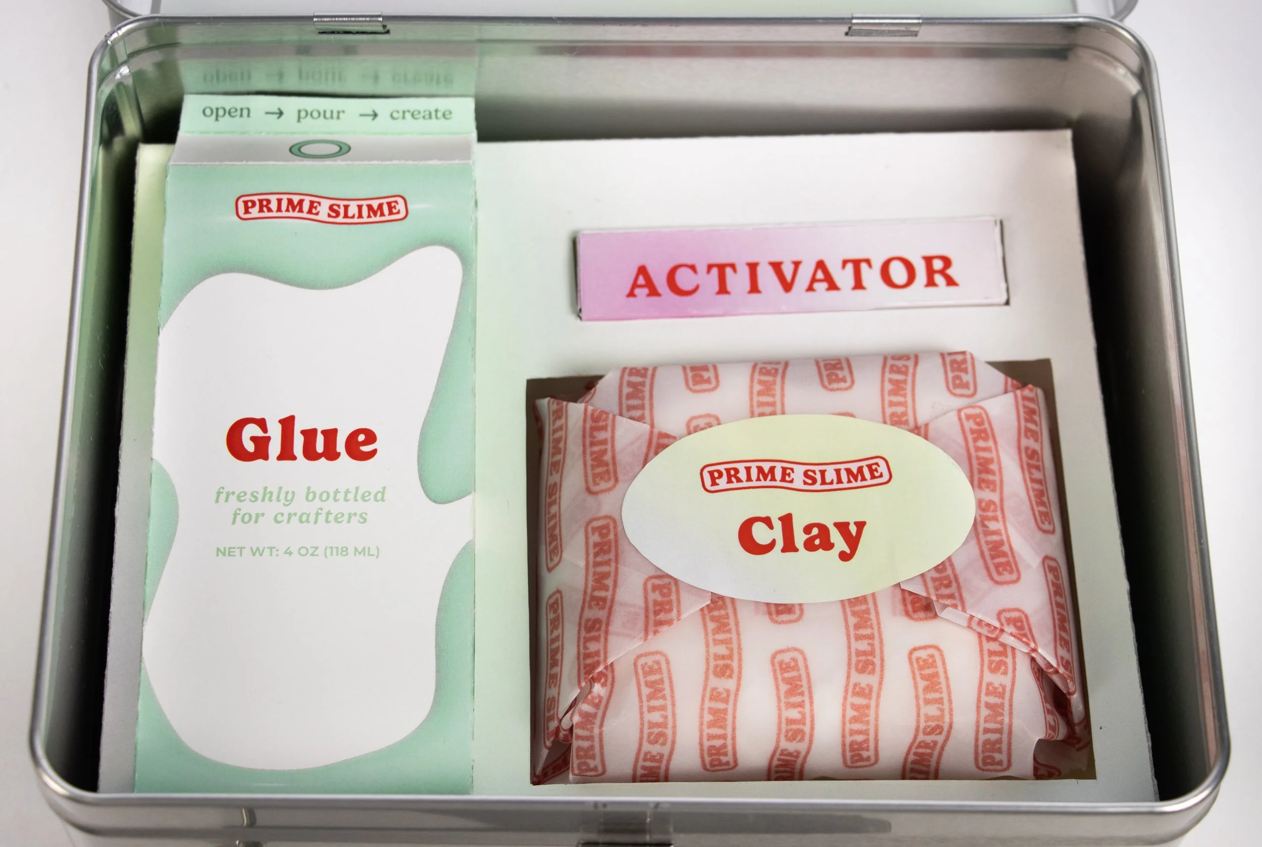 A metal box containing slime-making supplies, including a packet of Prime Slime glue, a package of Prime Slime clay, and an activation packet. Labels include 'Glue', 'Clay', and 'Activator'.