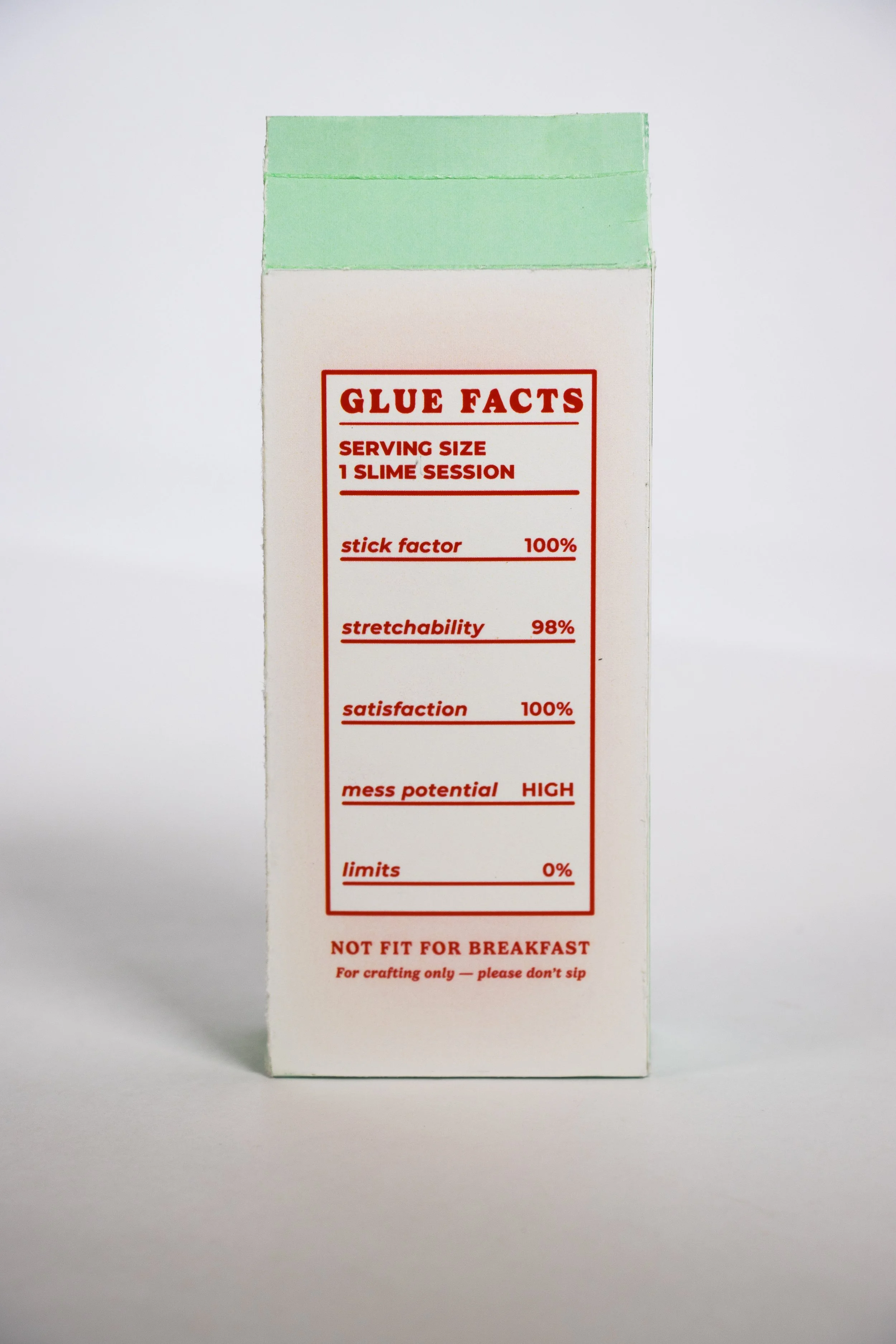 Packaging of slime with 'Glue Facts' label showing various statistics about the slime, including serving size, stickiness, stretchability, satisfaction, mess potential, and limits, with a note that it is not fit for breakfast.