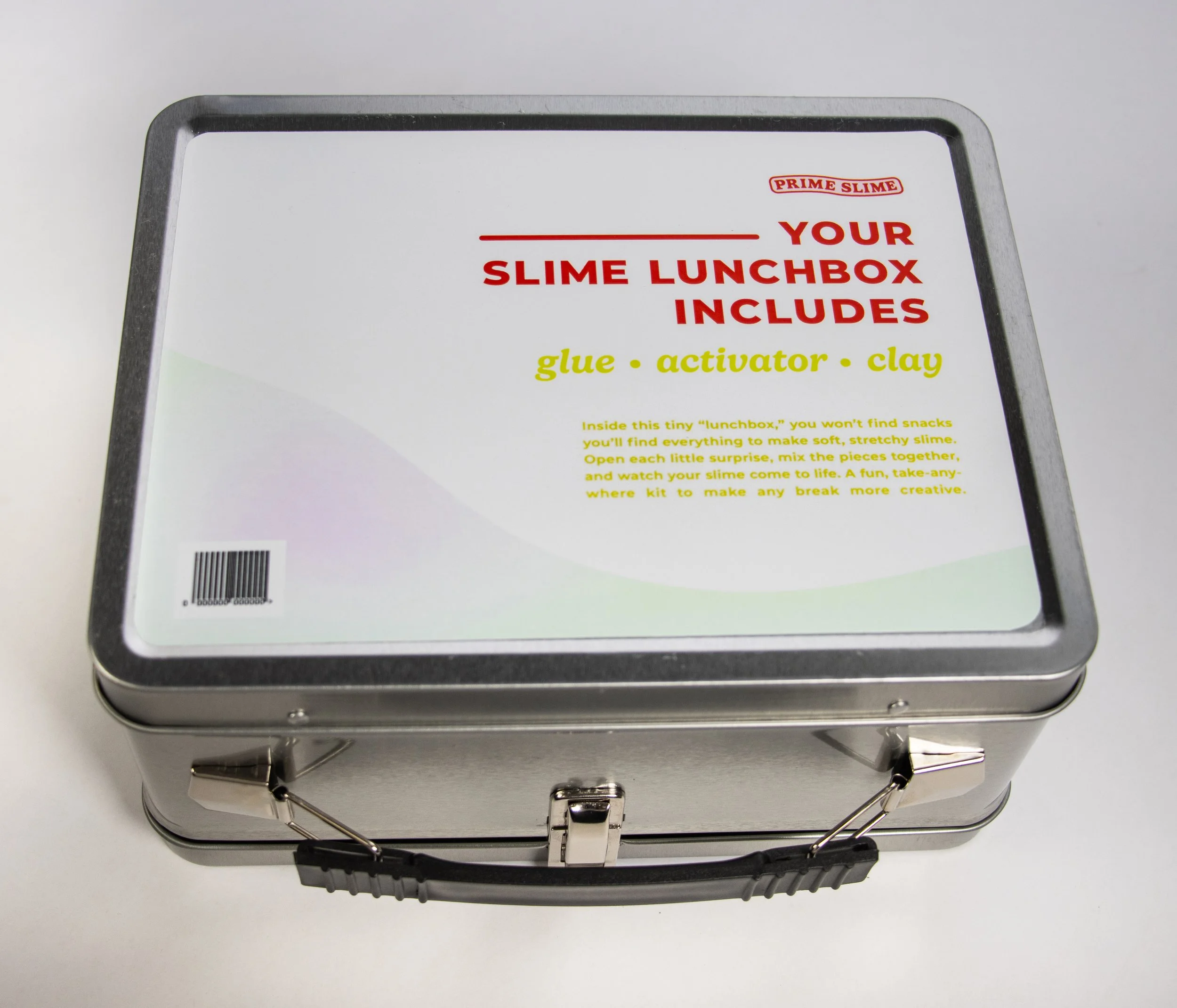 Metal lunchbox with a label advertising slime kit containing glue, activator, and clay.