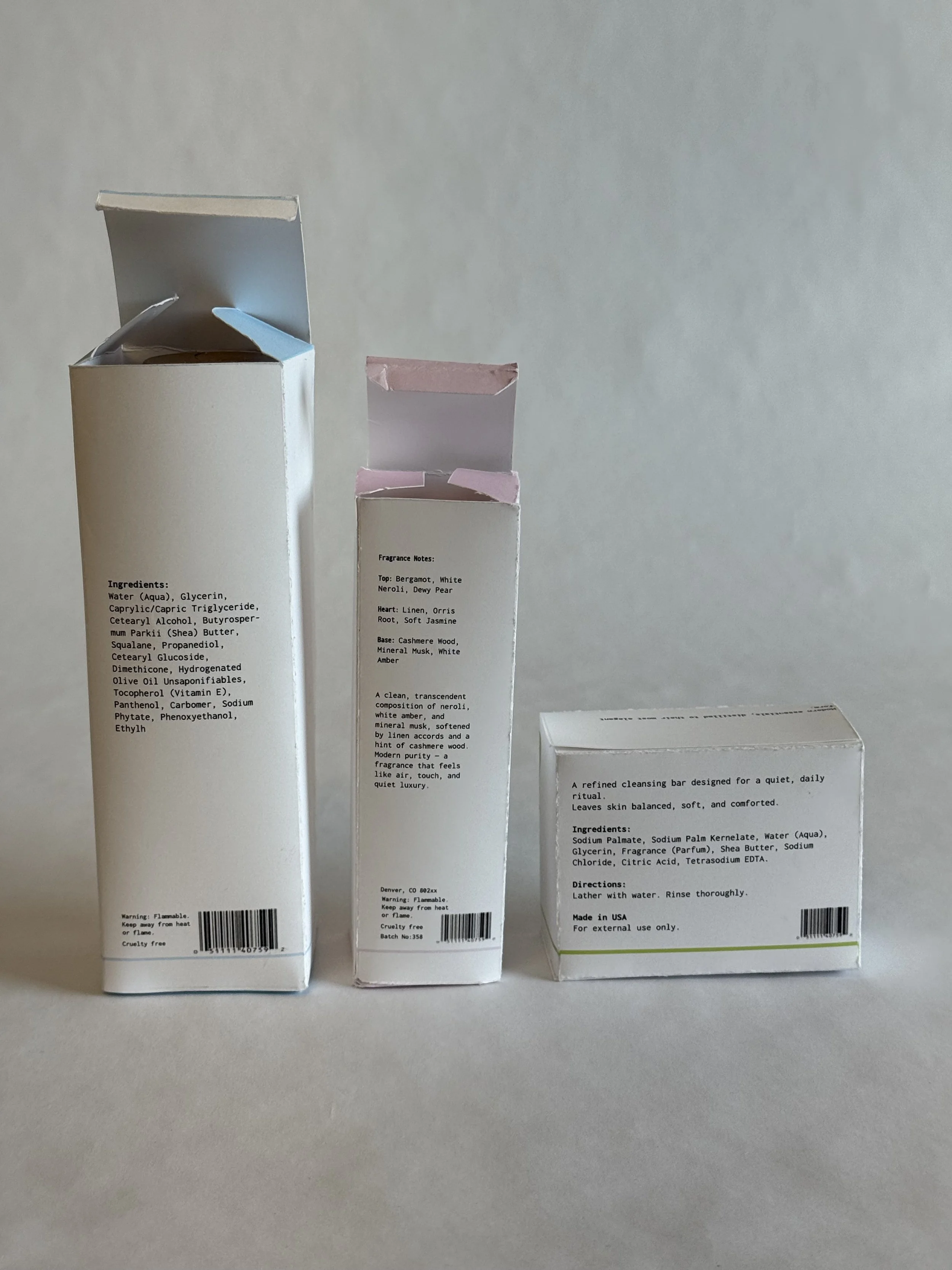 Three white boxes of personal care products standing upright on a surface against a plain background.