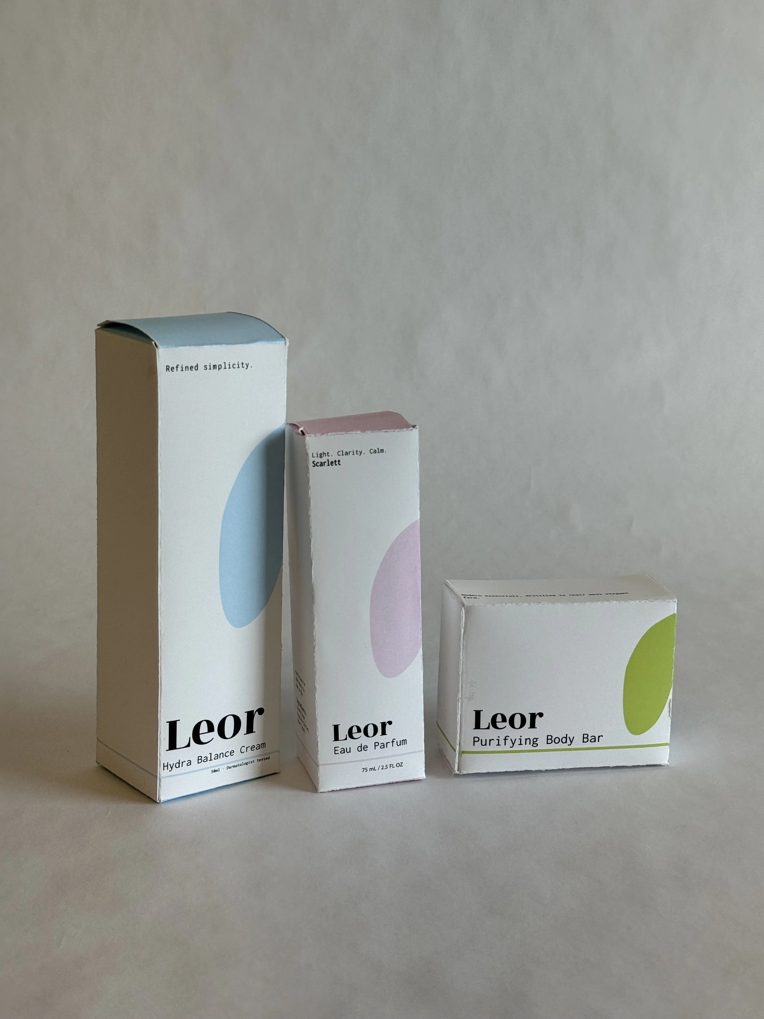 Three Leor skincare product boxes, including a Hydra Balance Cream, Eau de Parfum, and Purifying Body Bar, arranged on a plain background.