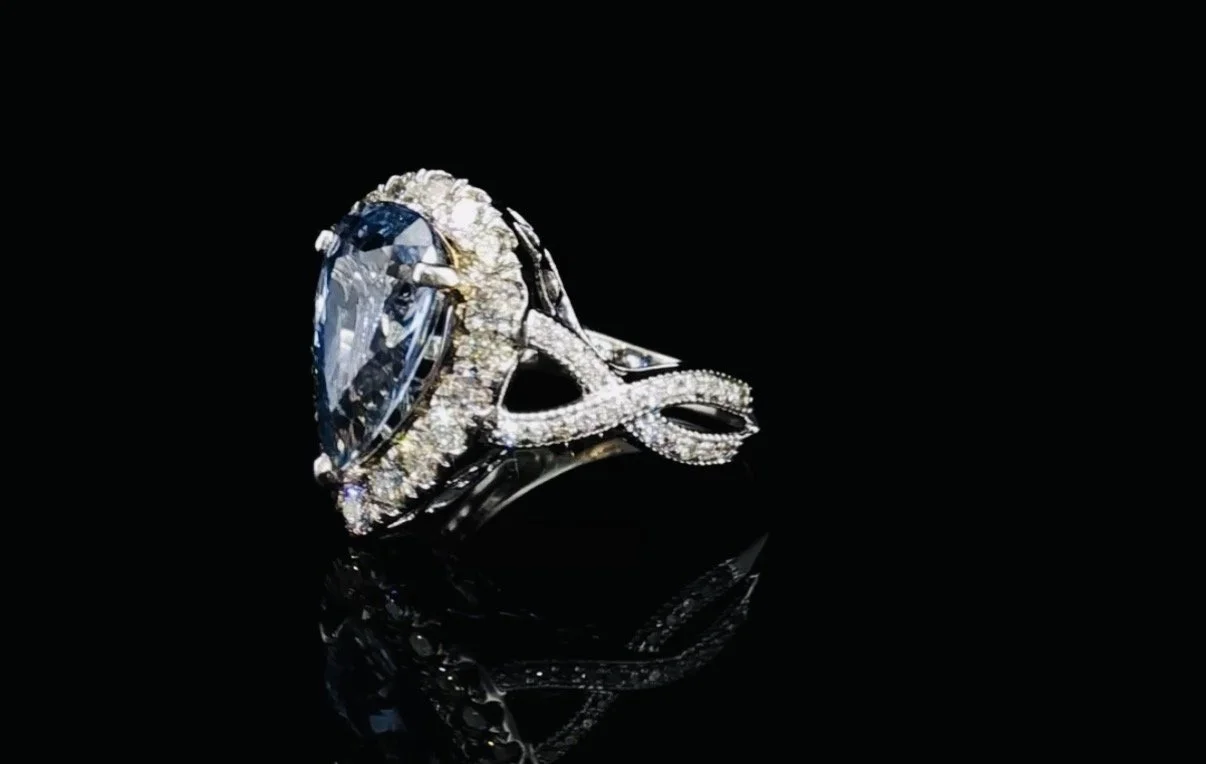 A close-up of a diamond ring on a black reflective surface.