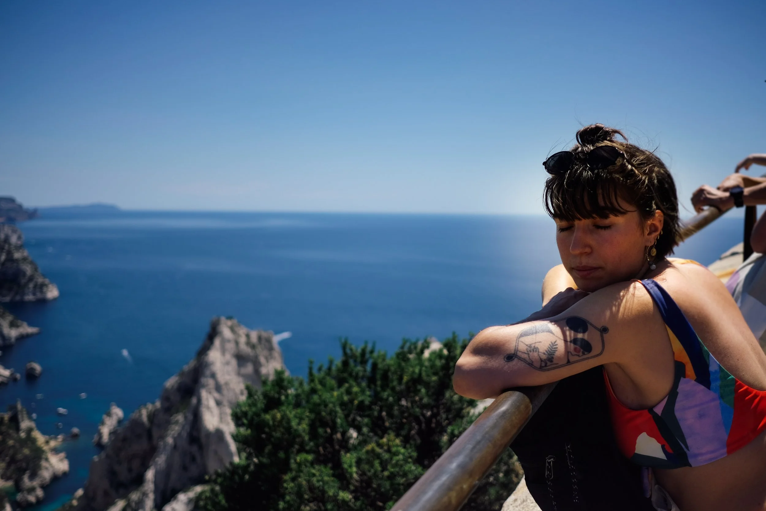 Jeune femme méditant ou se relaxant avec la mer et des rochers en arrière-plan