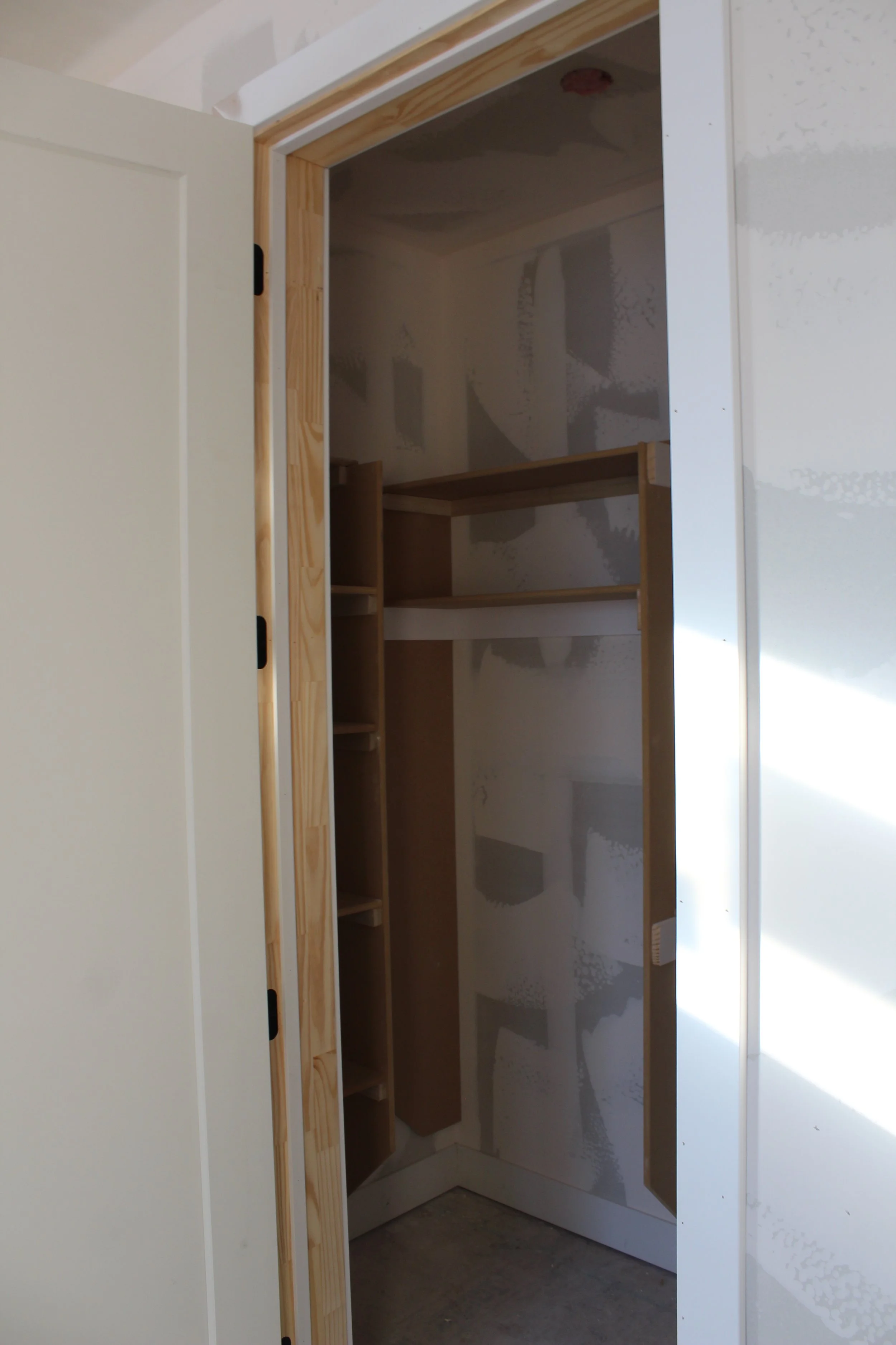 Empty closet with unfinished walls and built-in wooden shelves.