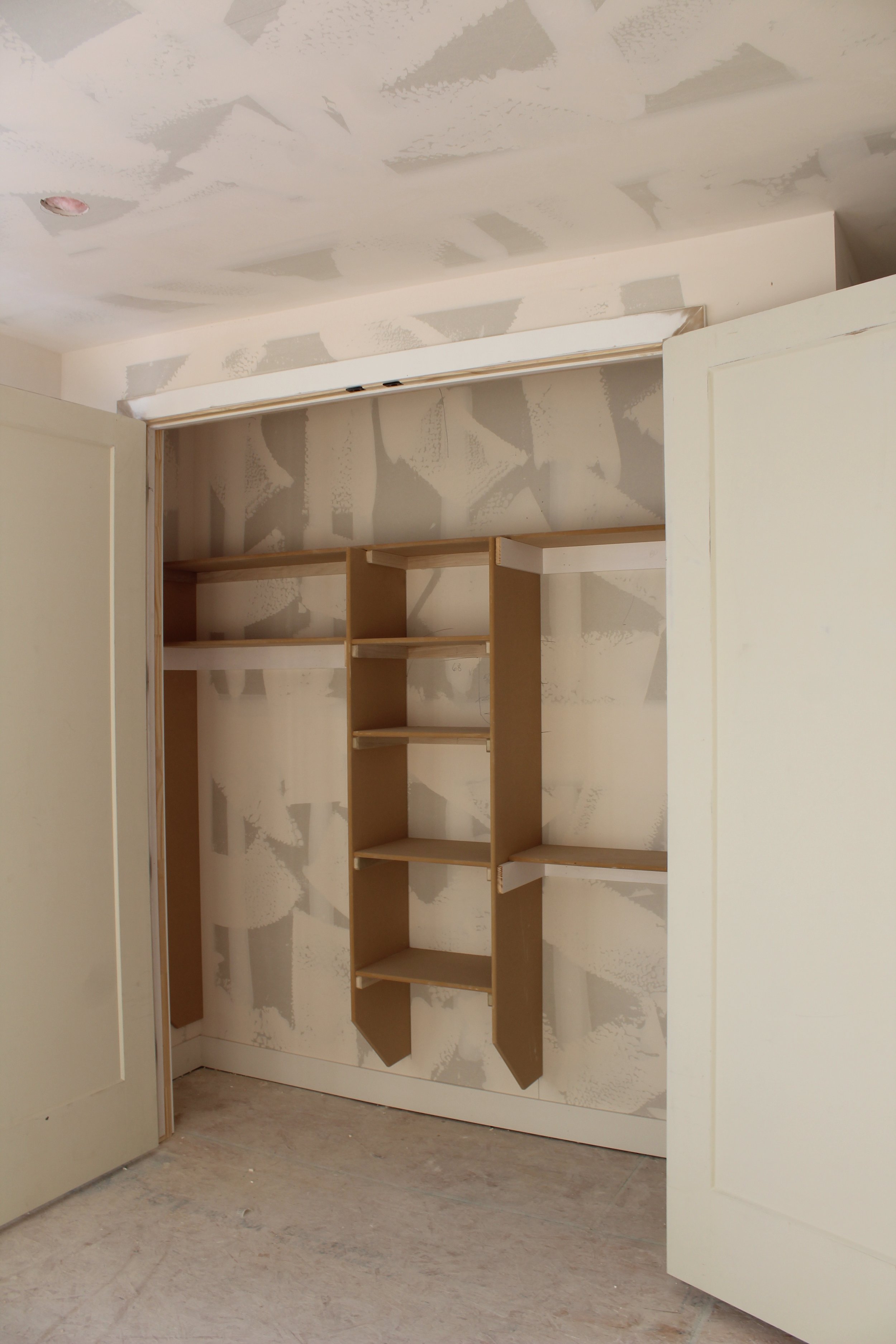 Interior of an unfinished closet with shelves and walls in the process of being painted or drywalled. This is a custom house constructed by Modern Traditions Inc     