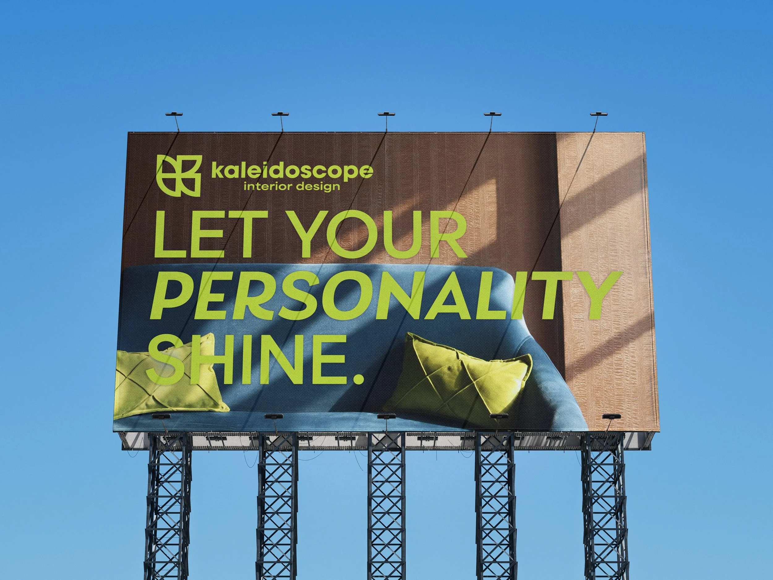Billboard outdoors for "Kaleidoscope Interior Design" with the words "Let Your Personality Shine" in lime green type over a photo with a turquoise couch and brown background.