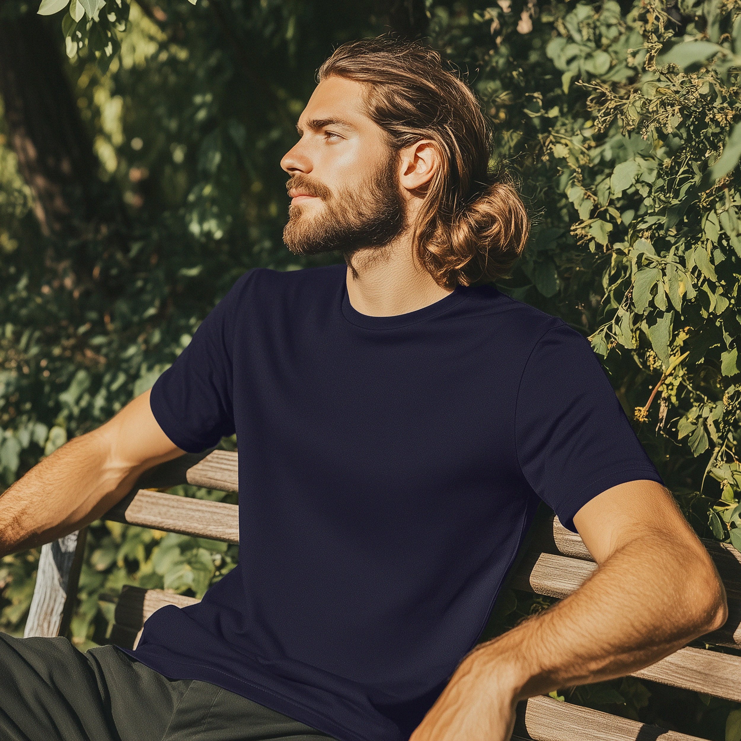 Male model wearing a dark Mental Health Made Wearable T-shirt, seated outdoors on a park bench, showing relaxed fit and everyday wearability.
