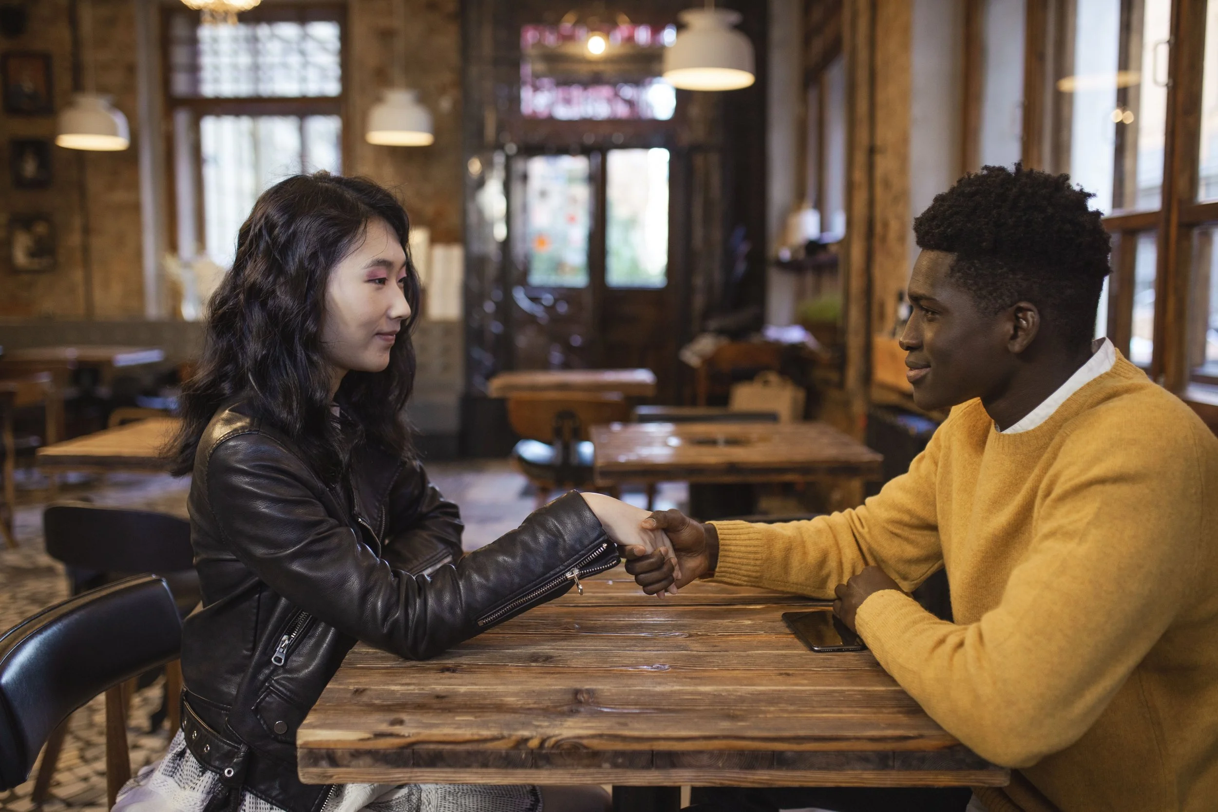 Man and woman greeting each other across a café table