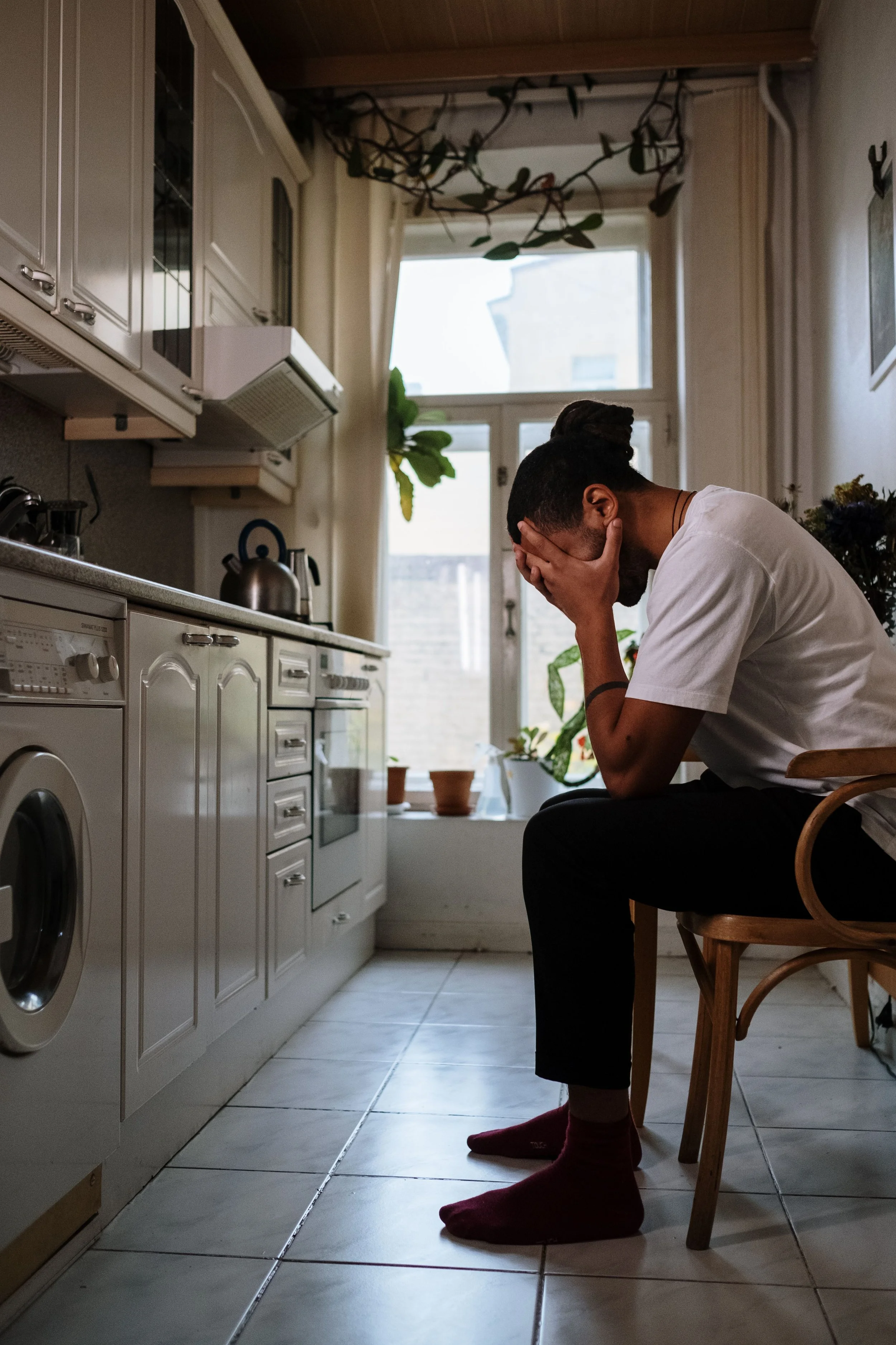 Man sitting alone at a kitchen table, quietly gathering his thoughts.