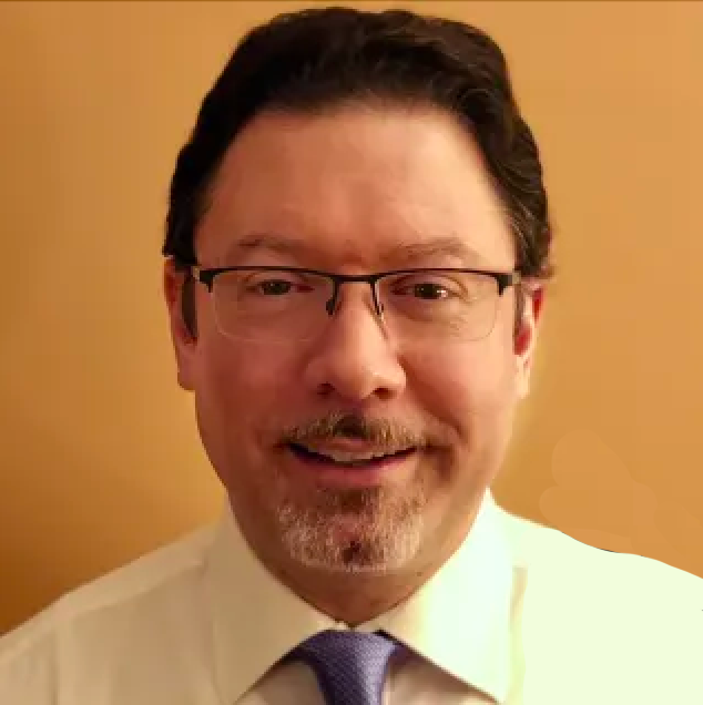 A man with glasses, dark hair, and a beard, smiling in front of a brown background, wearing a white shirt and a purple tie.