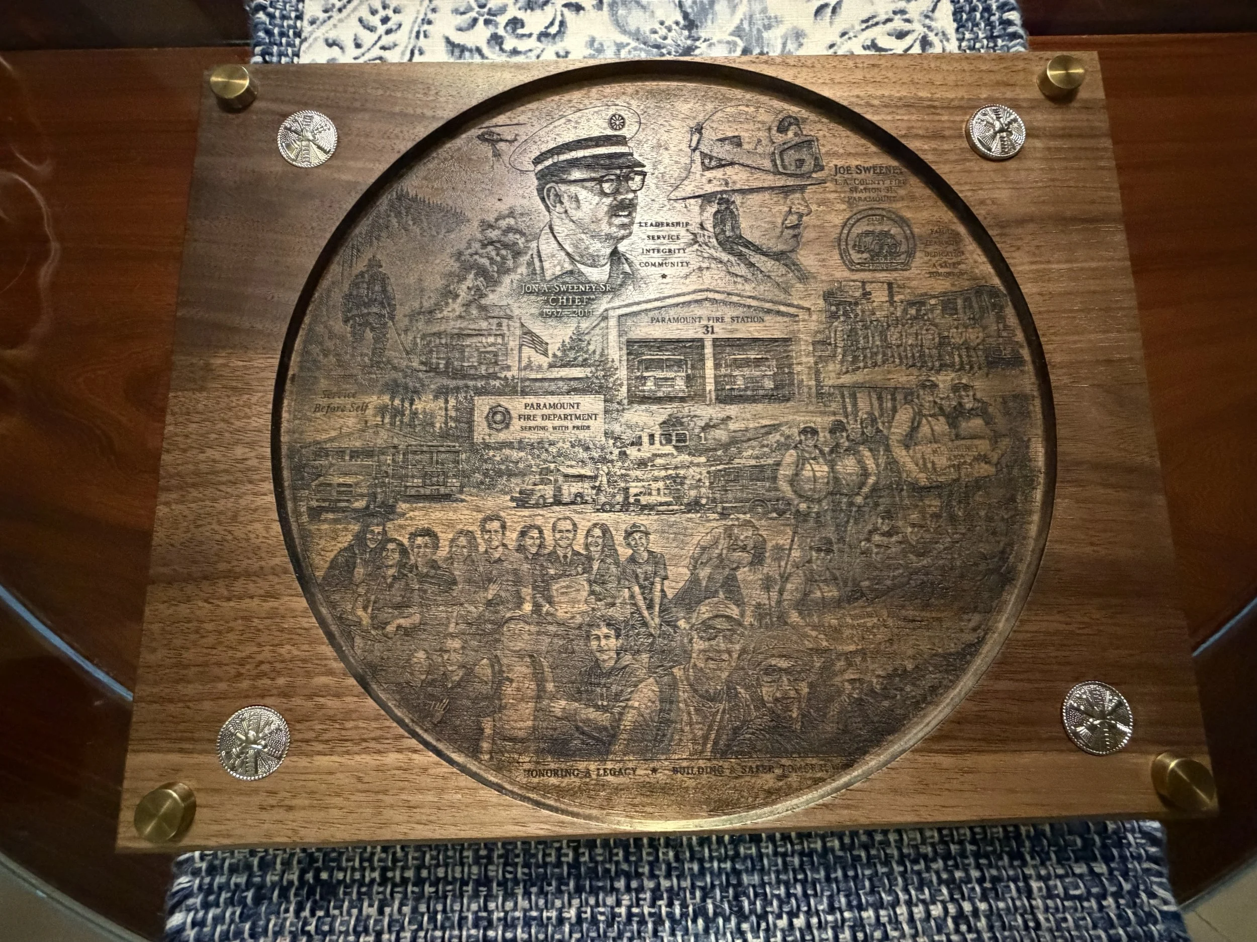 Walnut firefighter memorial commission with an engraved portrait mural and brass insignia.