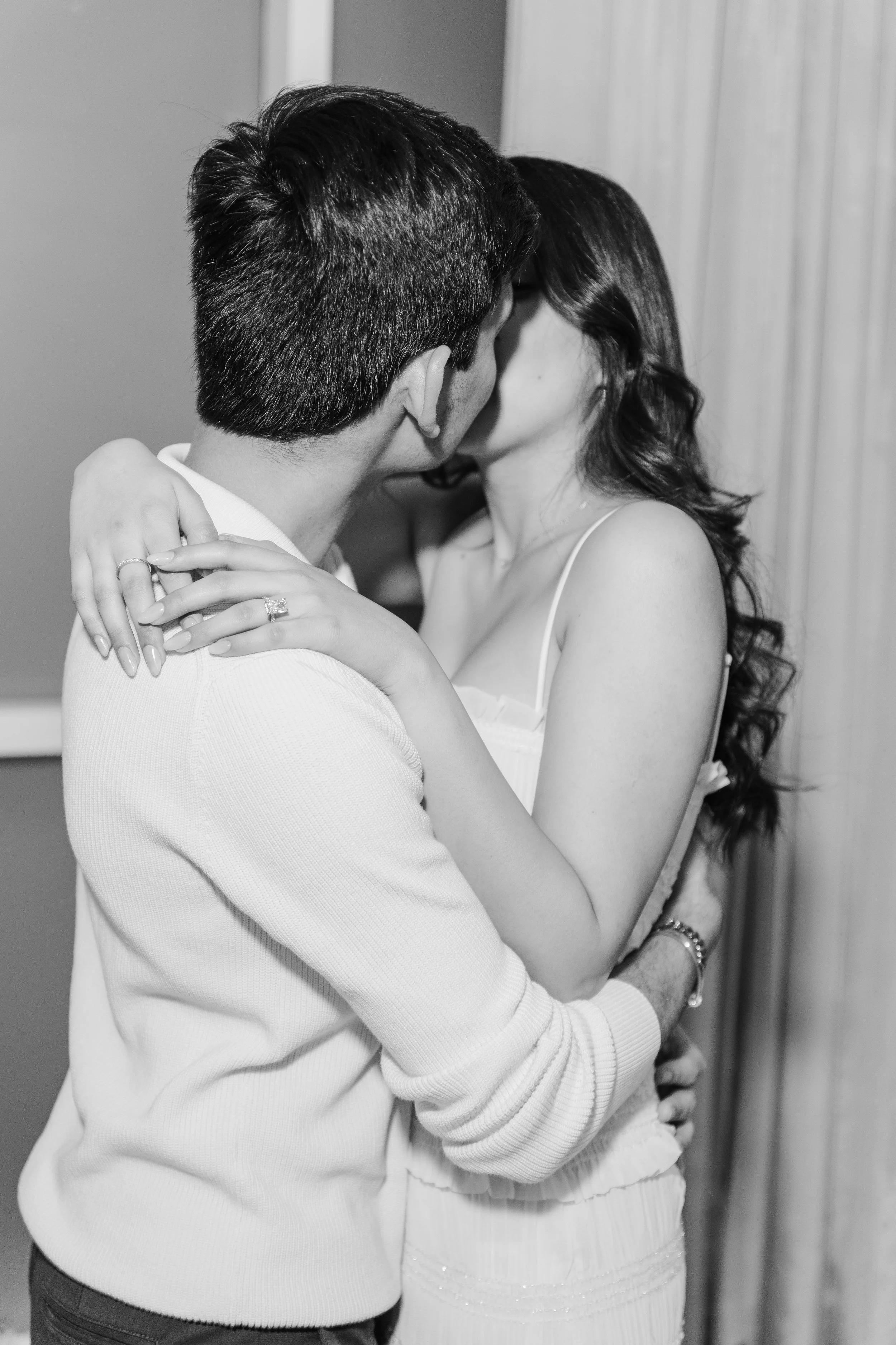A couple kissing closely with their arms wrapped around each other, capturing an intimate moment.