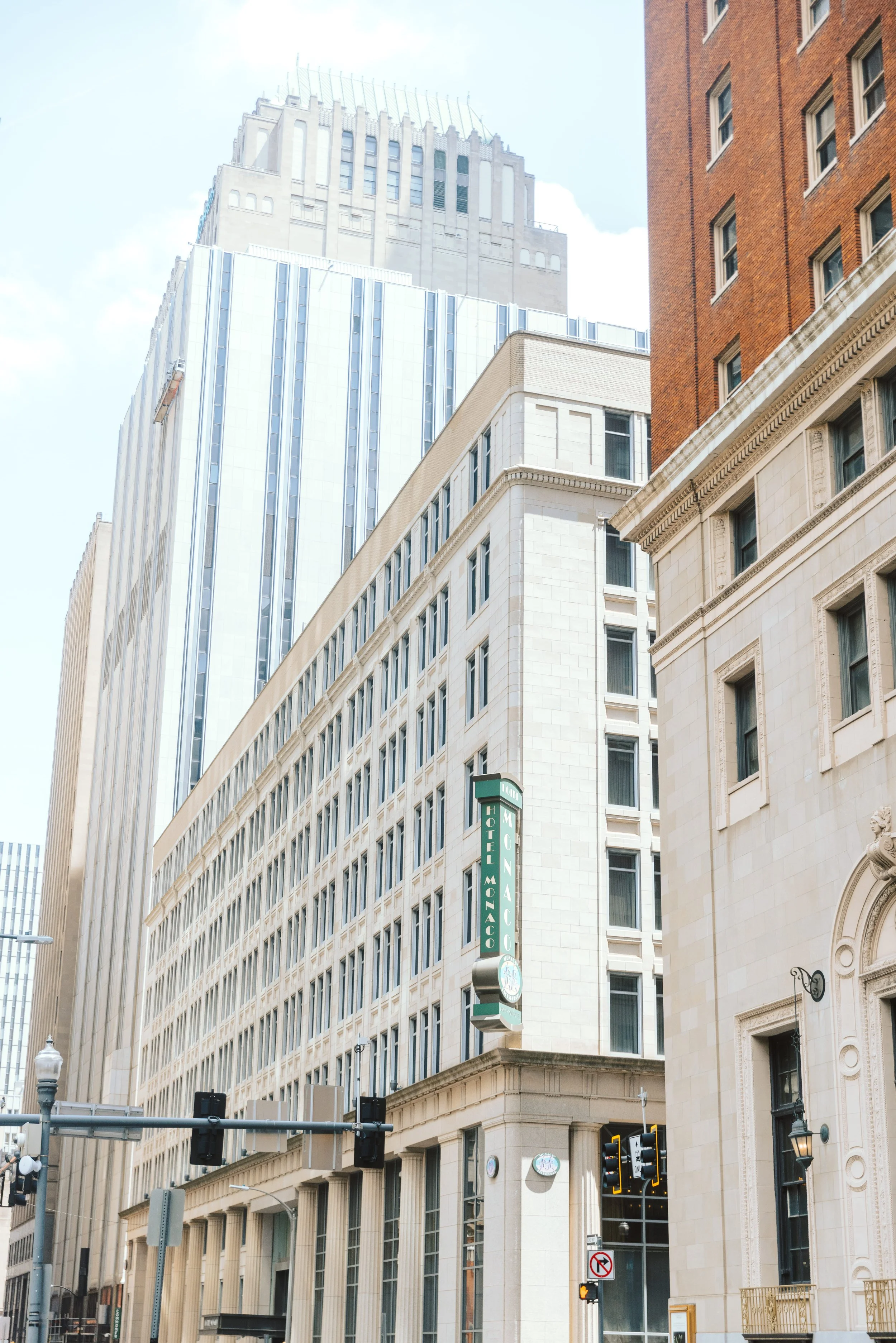 City street view with tall buildings, traffic lights, and a sign for Hotel Monico in a downtown area.