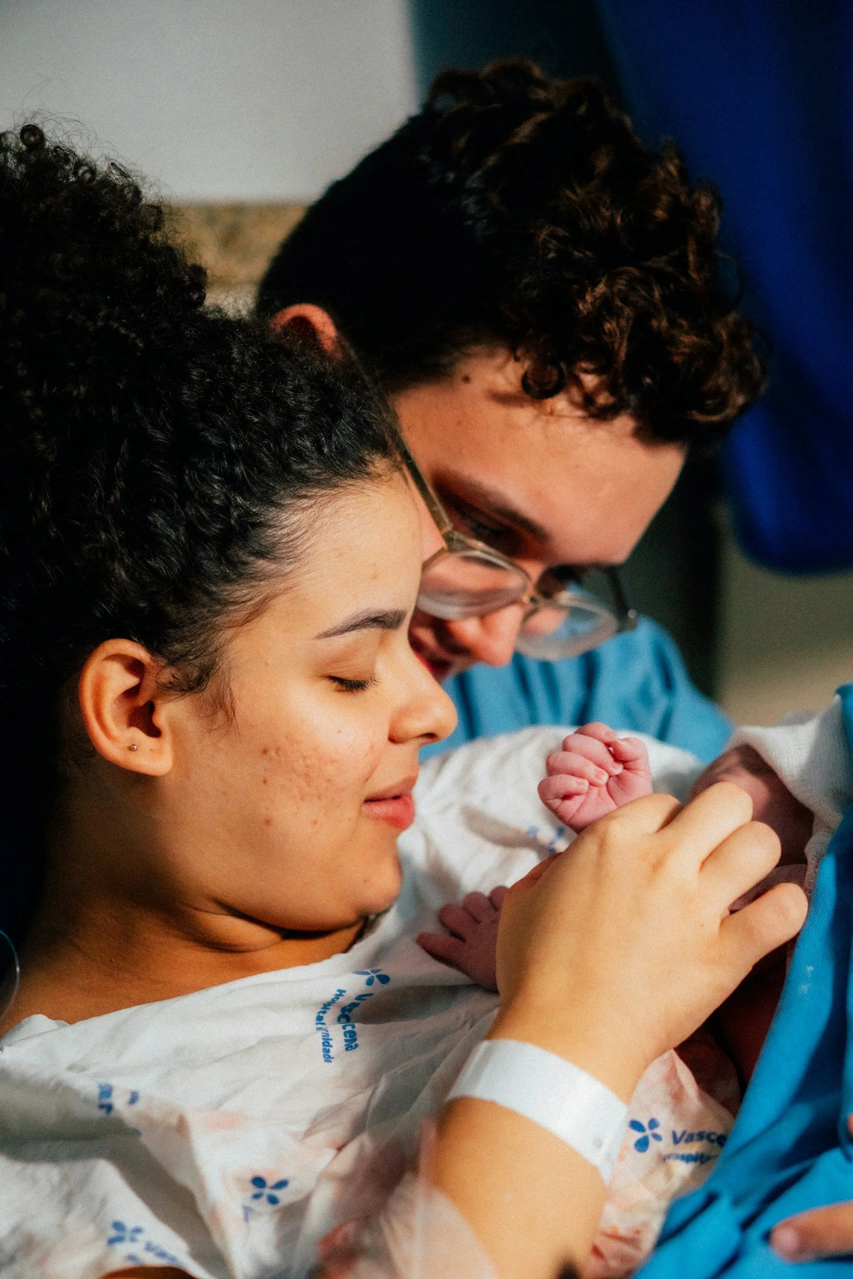 Baby is just born  with mother and father looking at it.