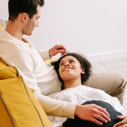 Couple pregnant looking at eachother lovingly.