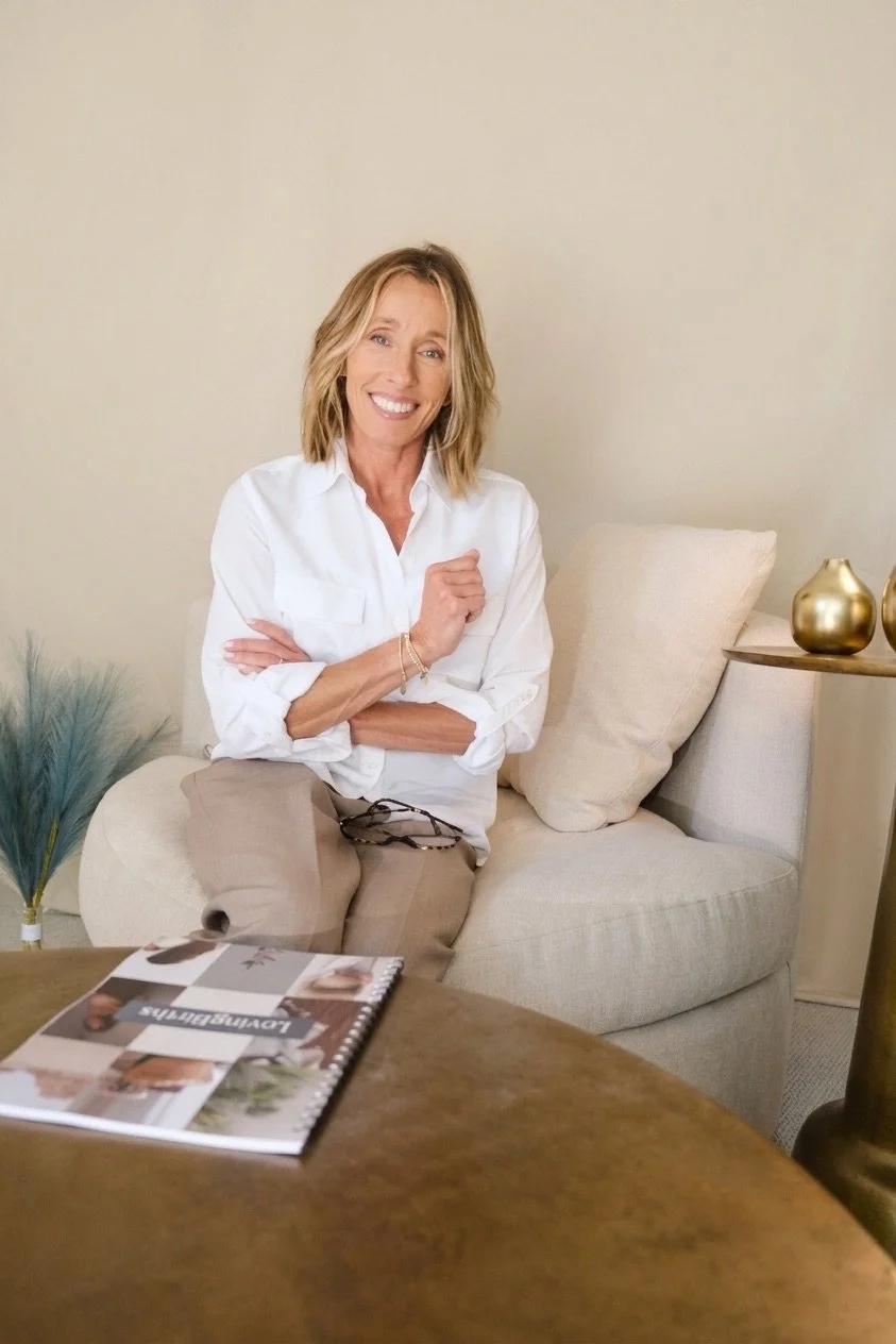 Taylor, founder of LovingBirths collective sitting on chair with childbirth workbook on table.