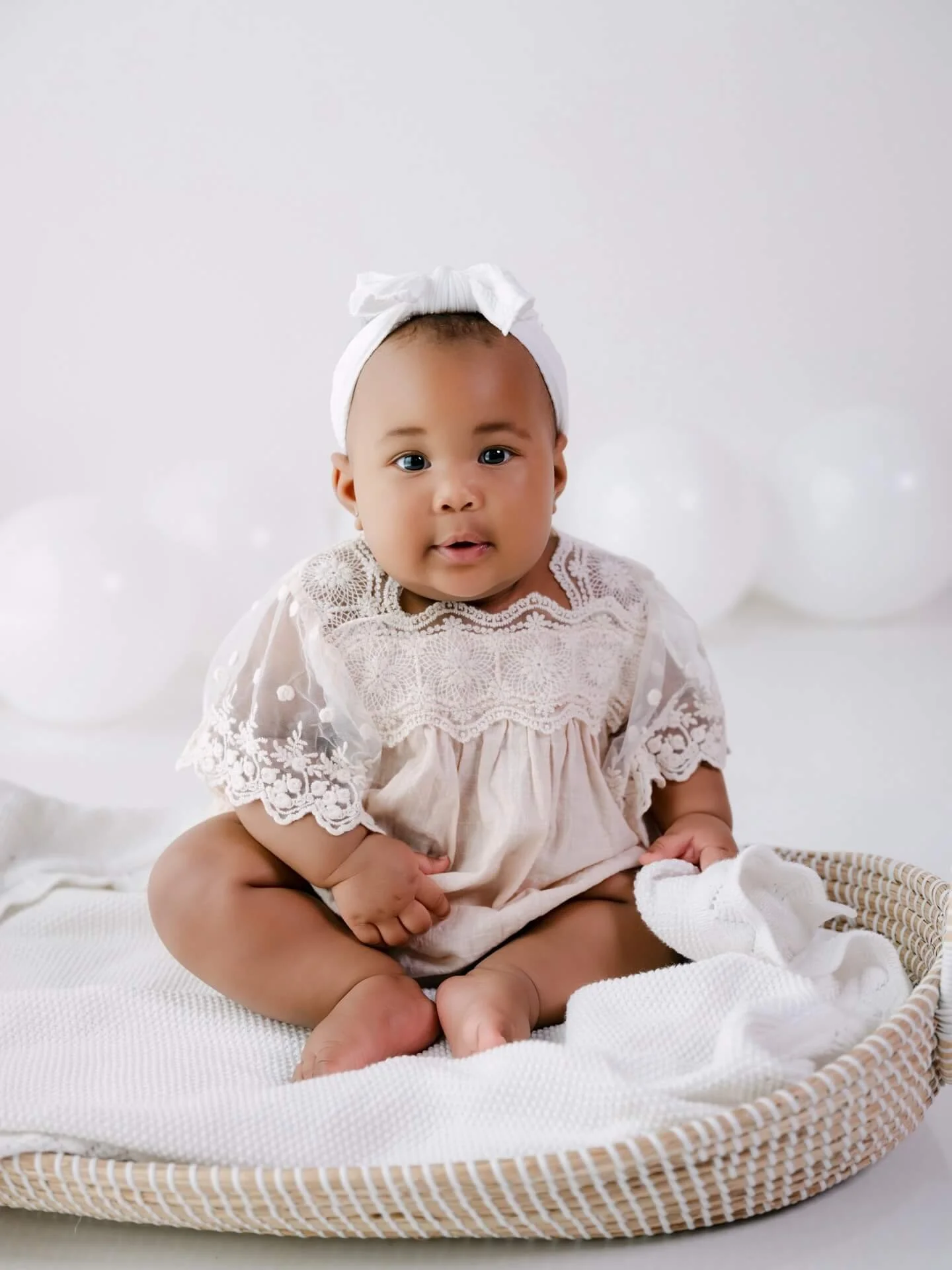 baby in white lace sitting up for photo