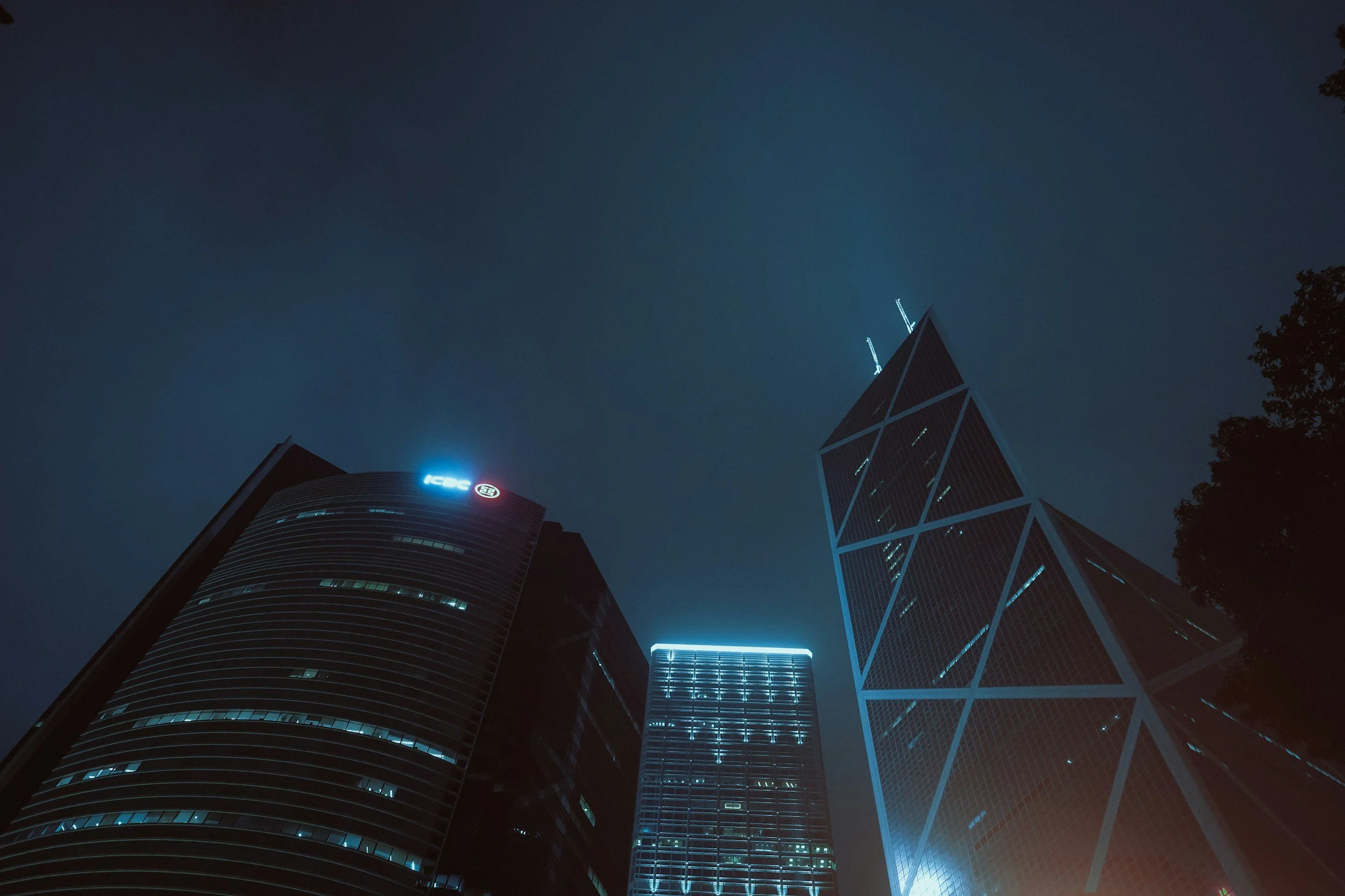 Nighttime view of three illuminated skyscrapers in a city, including the ICG building and a tall building with diagonal white lines on its facade.