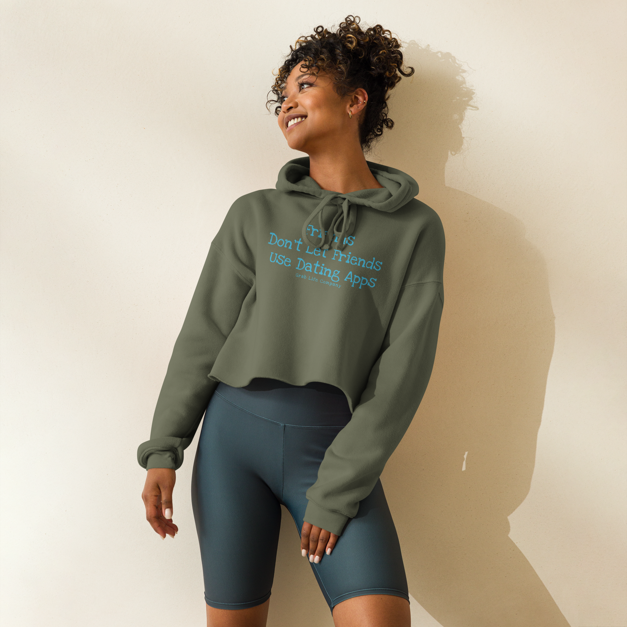 Grab Life Company cropped hoodie with Friends don't let Friends use Dating Apps printed on the front in blue on military green sweatshirt.