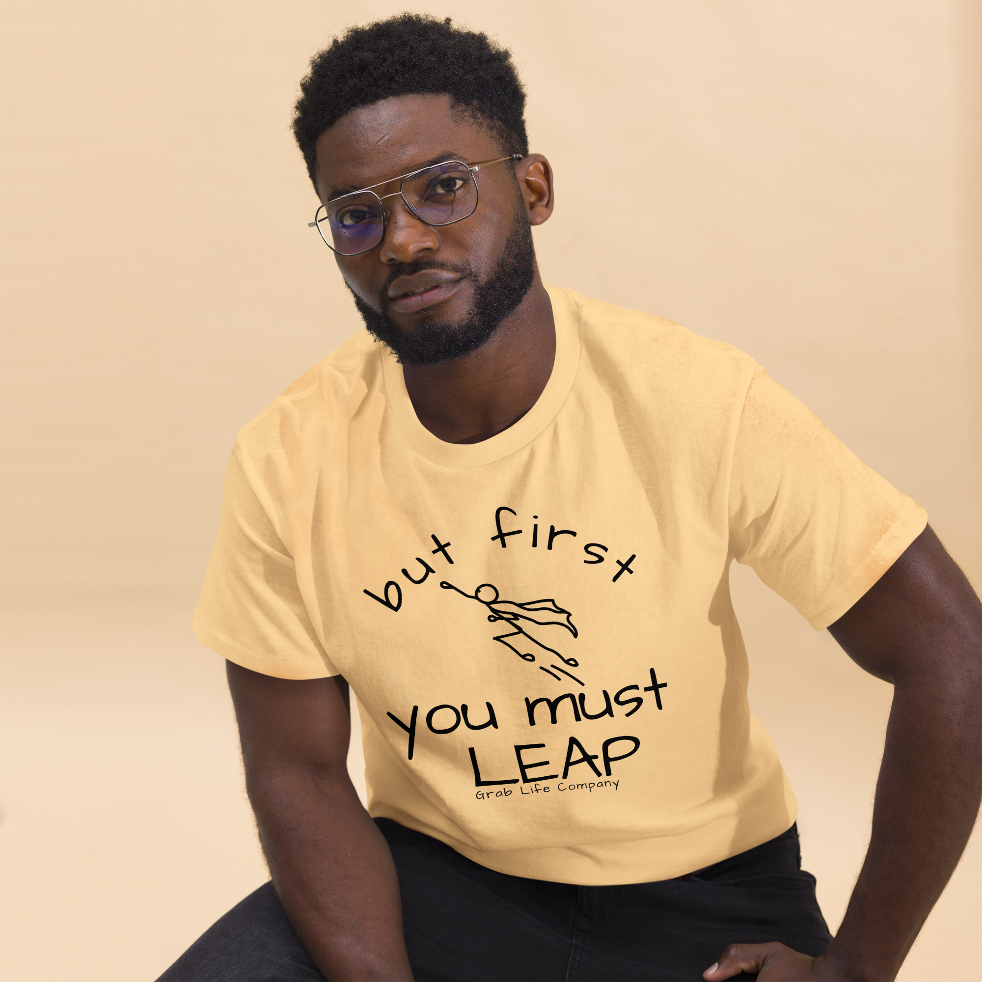 Grab Life Company unisex t-shirt with but first you must Leap printed on the front in black on a yellow tee. Image shows a man wearing the shirt.