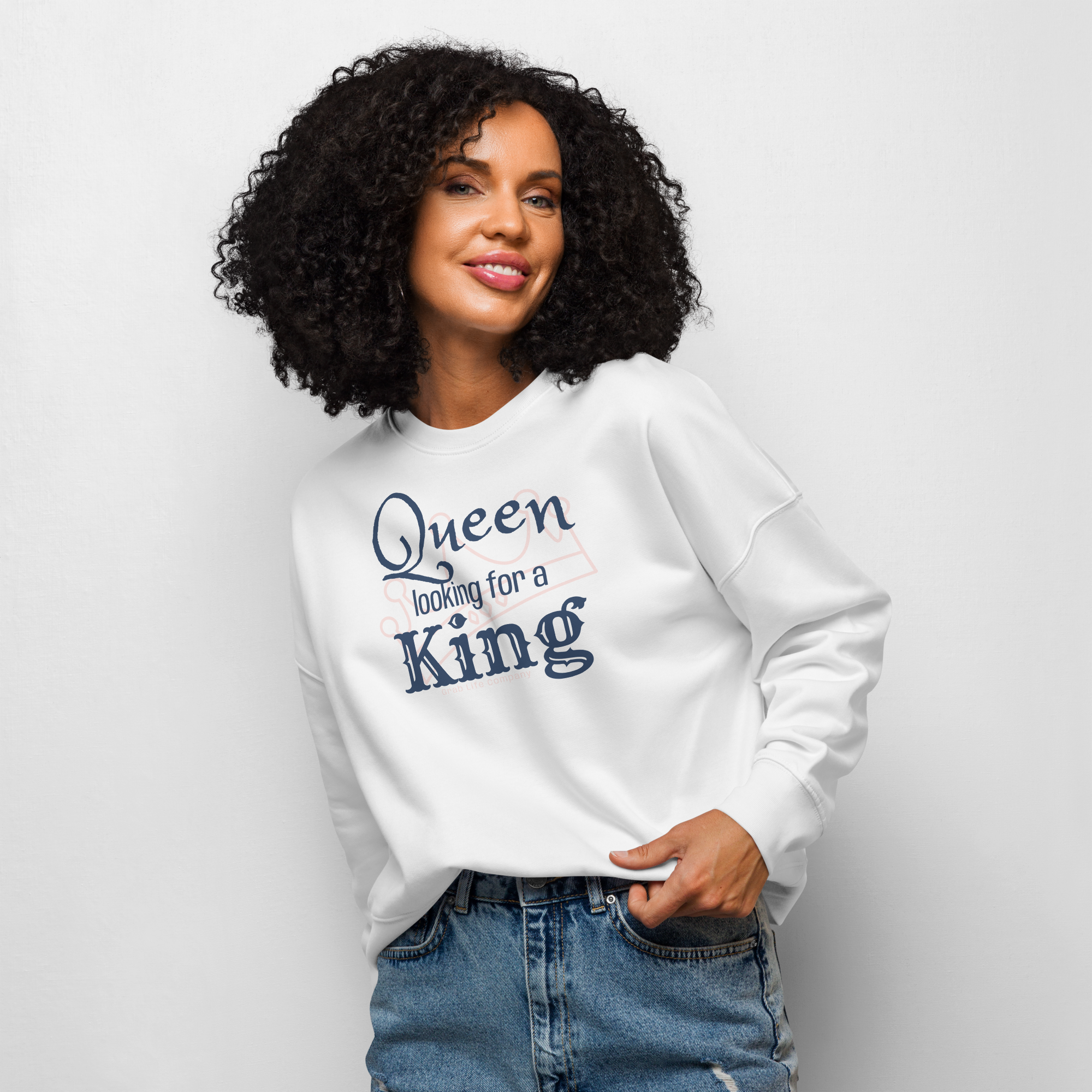 Grab Life Company women's crew neck sweatshirt with Queen looking for a King on the front printed in navy blue on a white sweatshirt. Image shows a woman wearing the shirt.