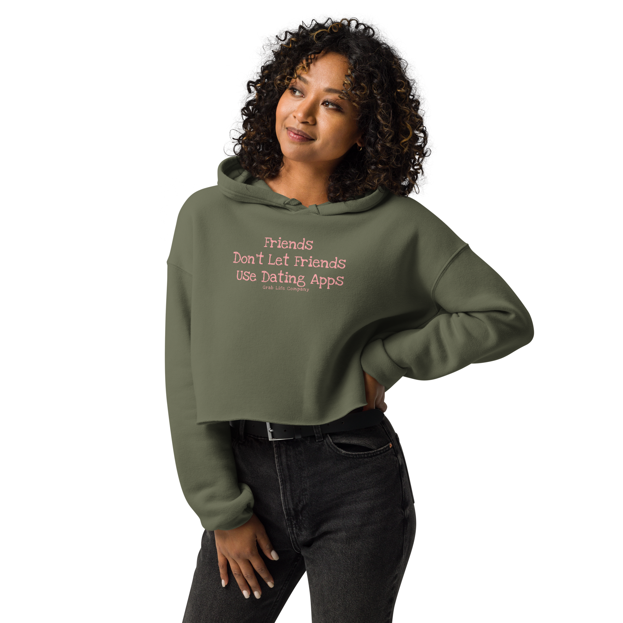 Grab Life Company cropped hoodie with Friends don't let Friends use Dating Apps printed on the front in pink on military green sweatshirt. Image shows a woman wearing the hoodie.
