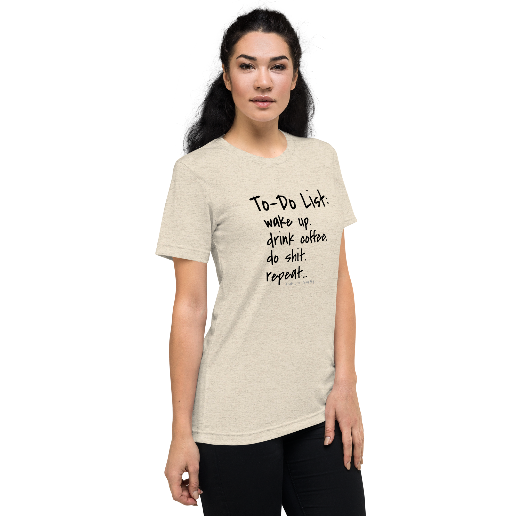 Grab Life Company unisex t-shirt with To-Do List: wake up. drink coffee. do shit. repeat. written on the front in black on a oatmeal triblend tee. Image shows a woman wearing the shirt.