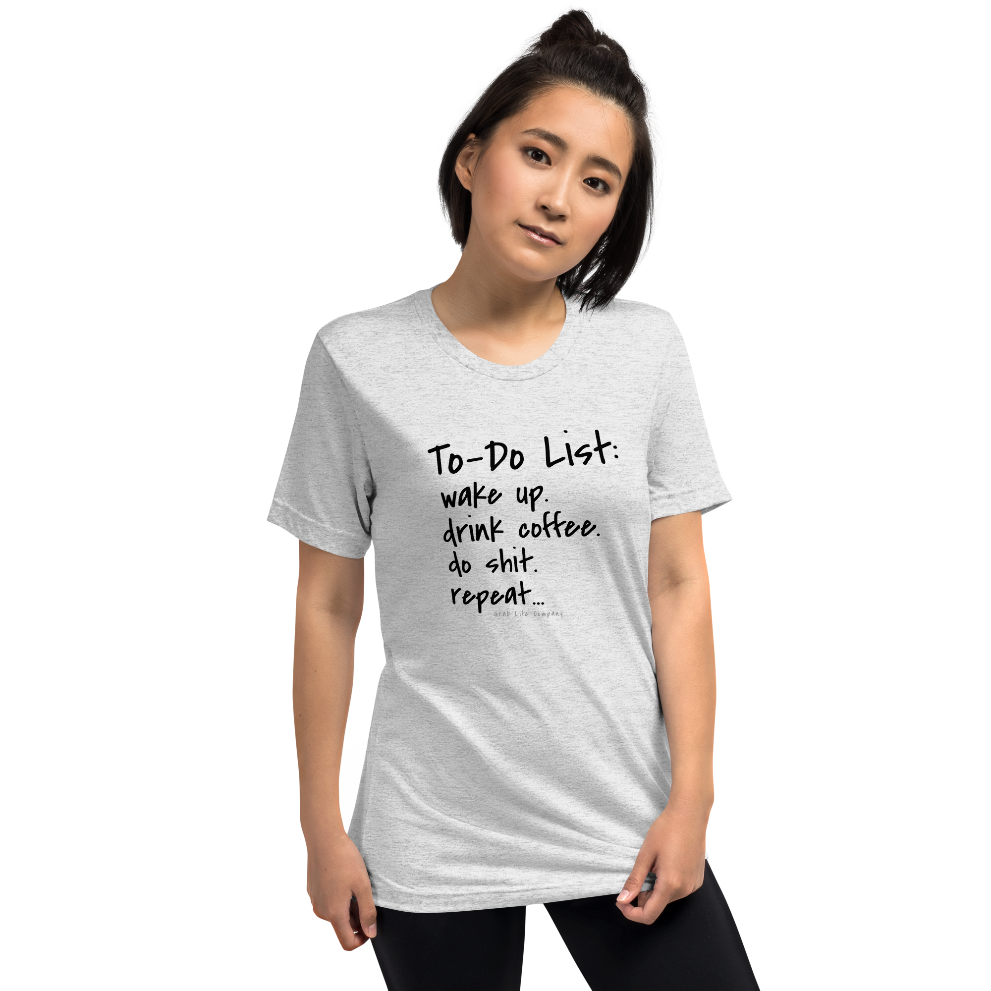Grab Life Company unisex t-shirt with To-Do List: wake up. drink coffee. do shit. repeat. written on the front in black on a white fleck triblend tee. Image shows a woman wearing the shirt.