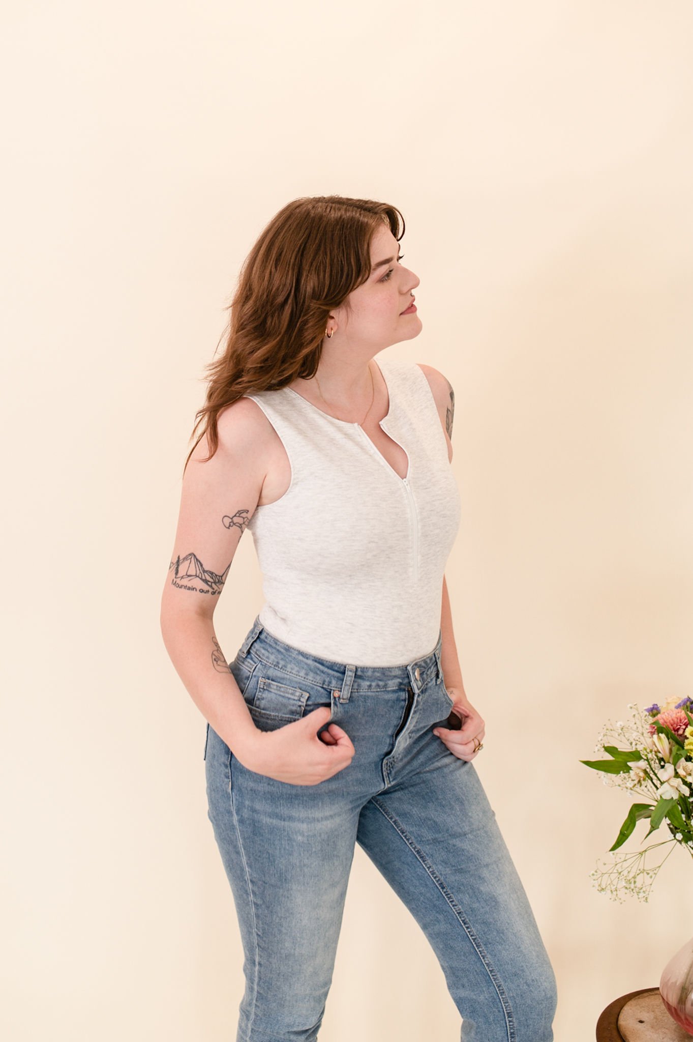 Sleeveless cream half-zip bodysuit with a fitted silhouette and zip-front neckline.