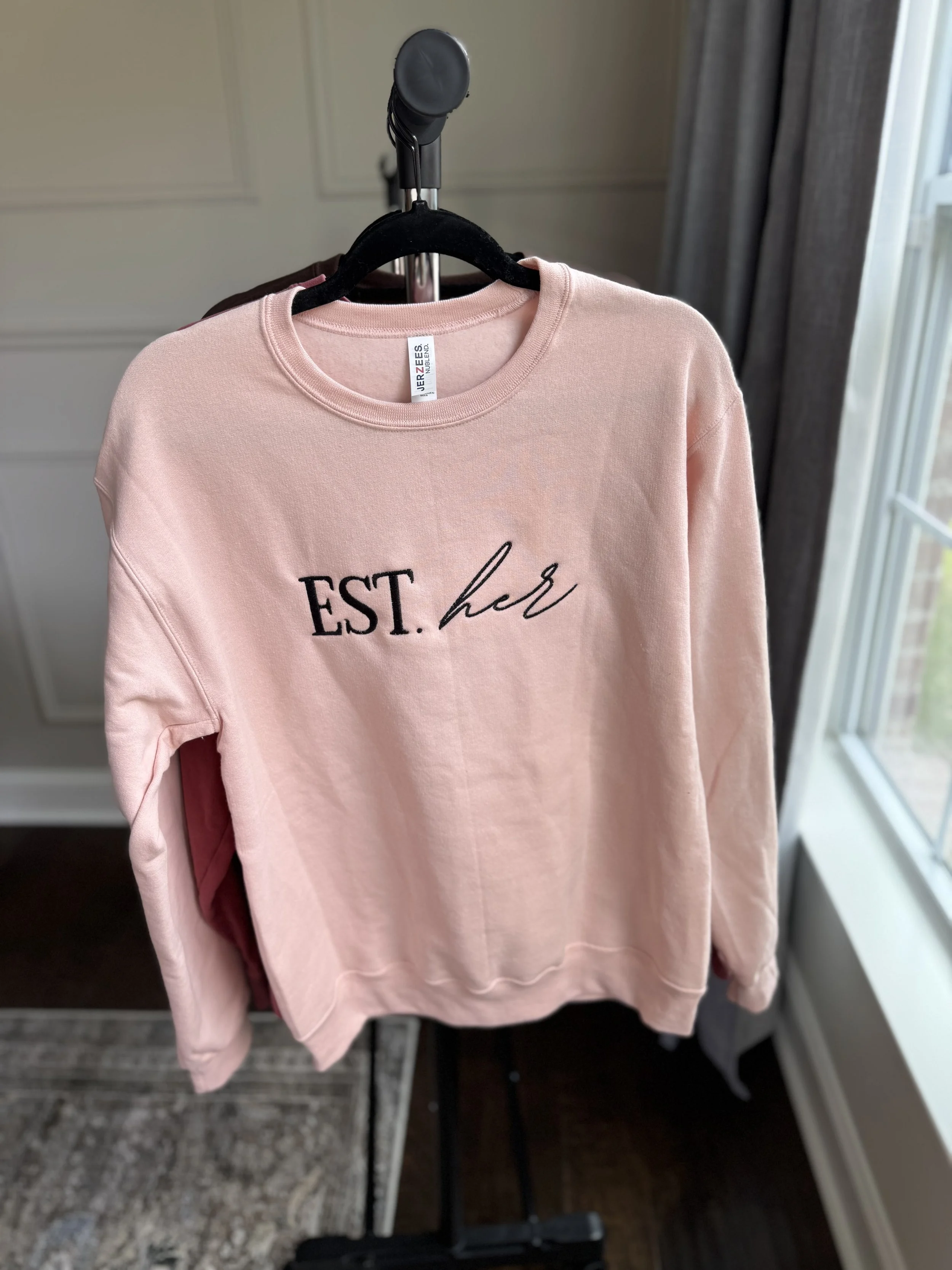 Dusty rose sweatshirt with Esther logo graphic.