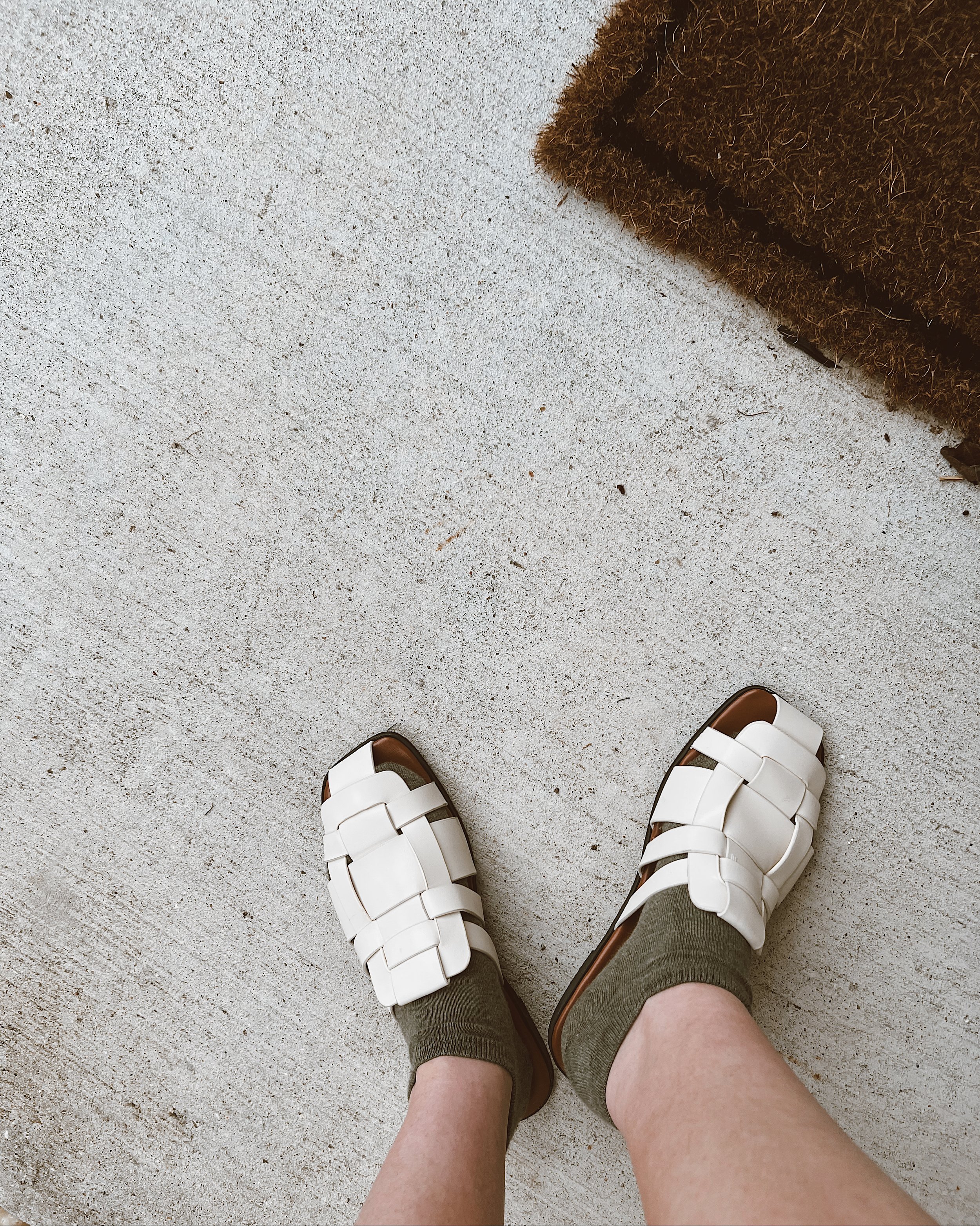 Cream woven flat mules with an open-toe design.