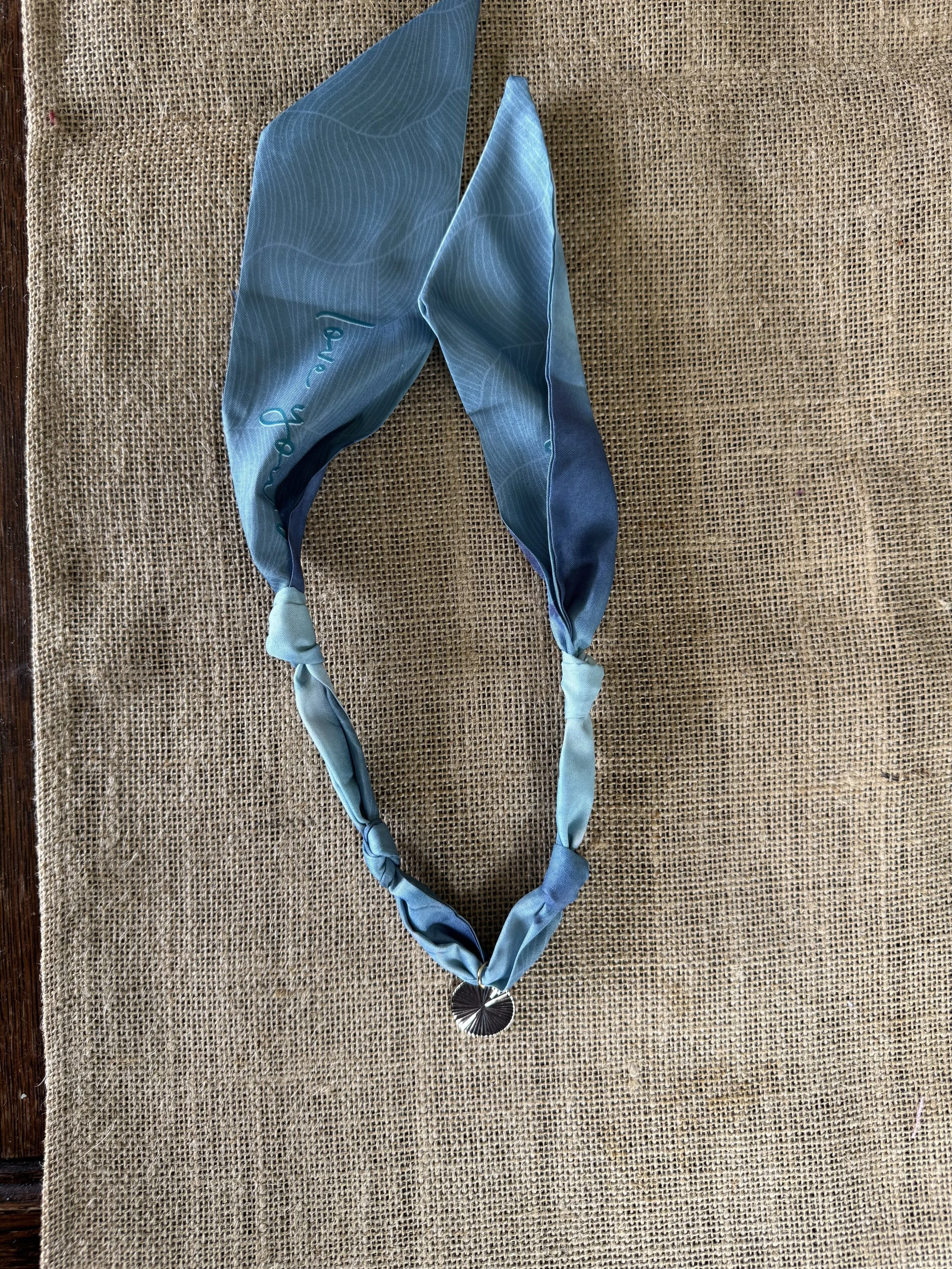 Blue statement necklace with fabric and bead details.