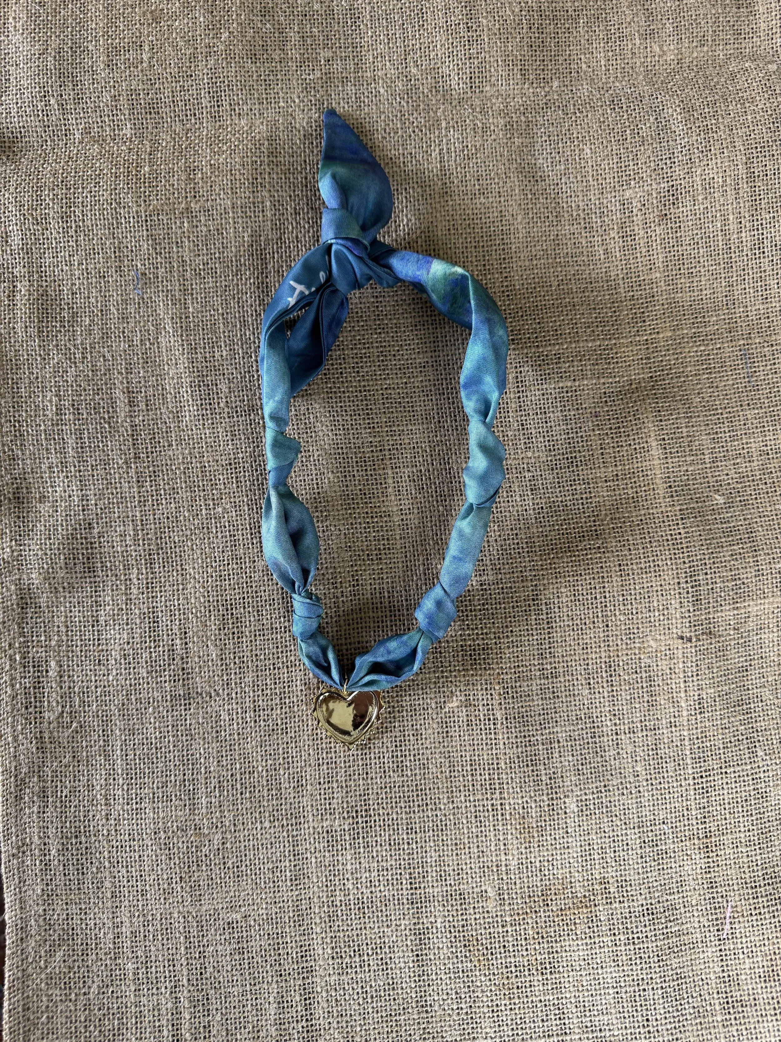 Blue statement necklace with fabric and bead details.