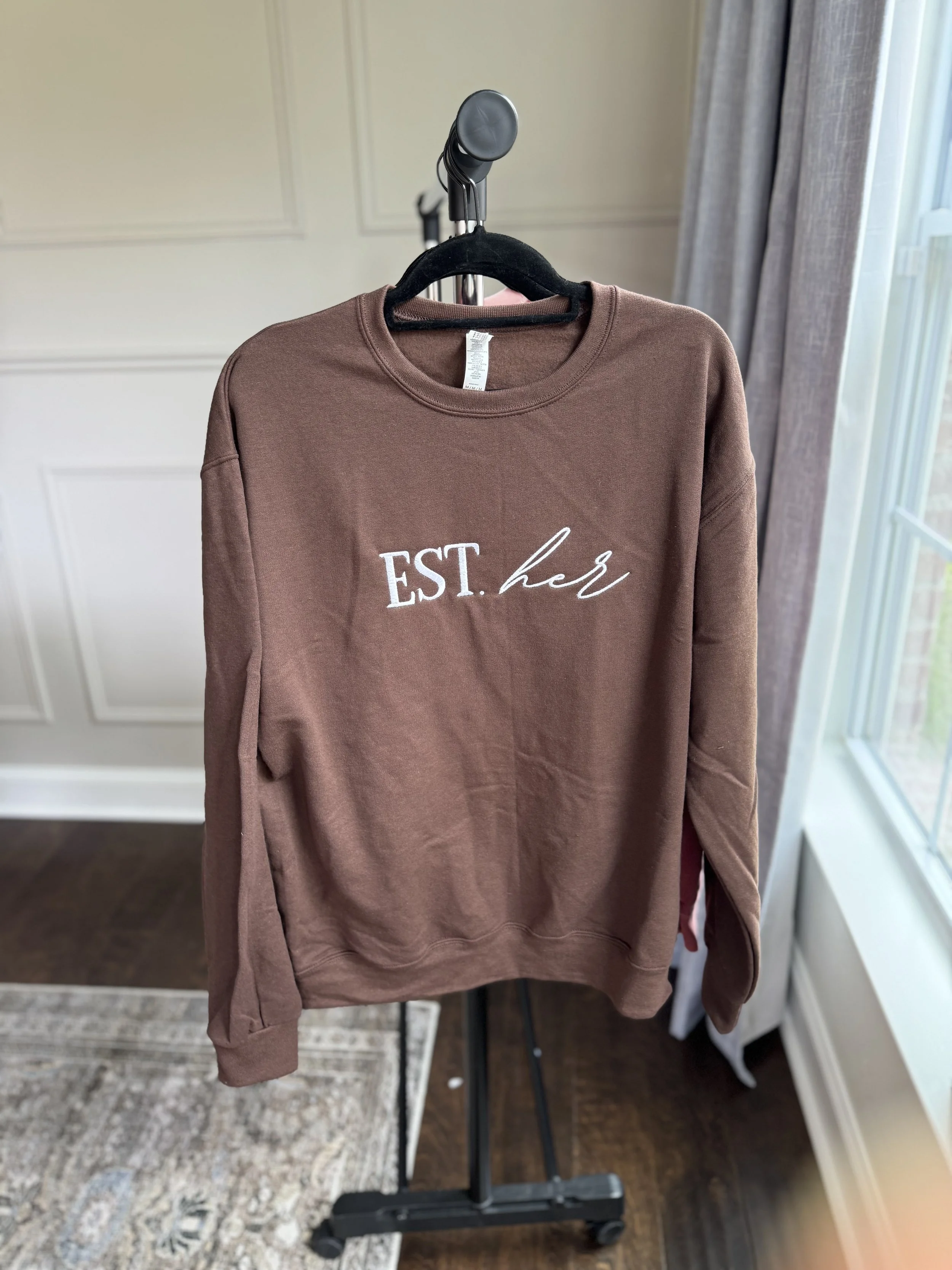Dusty rose sweatshirt with Esther logo graphic.