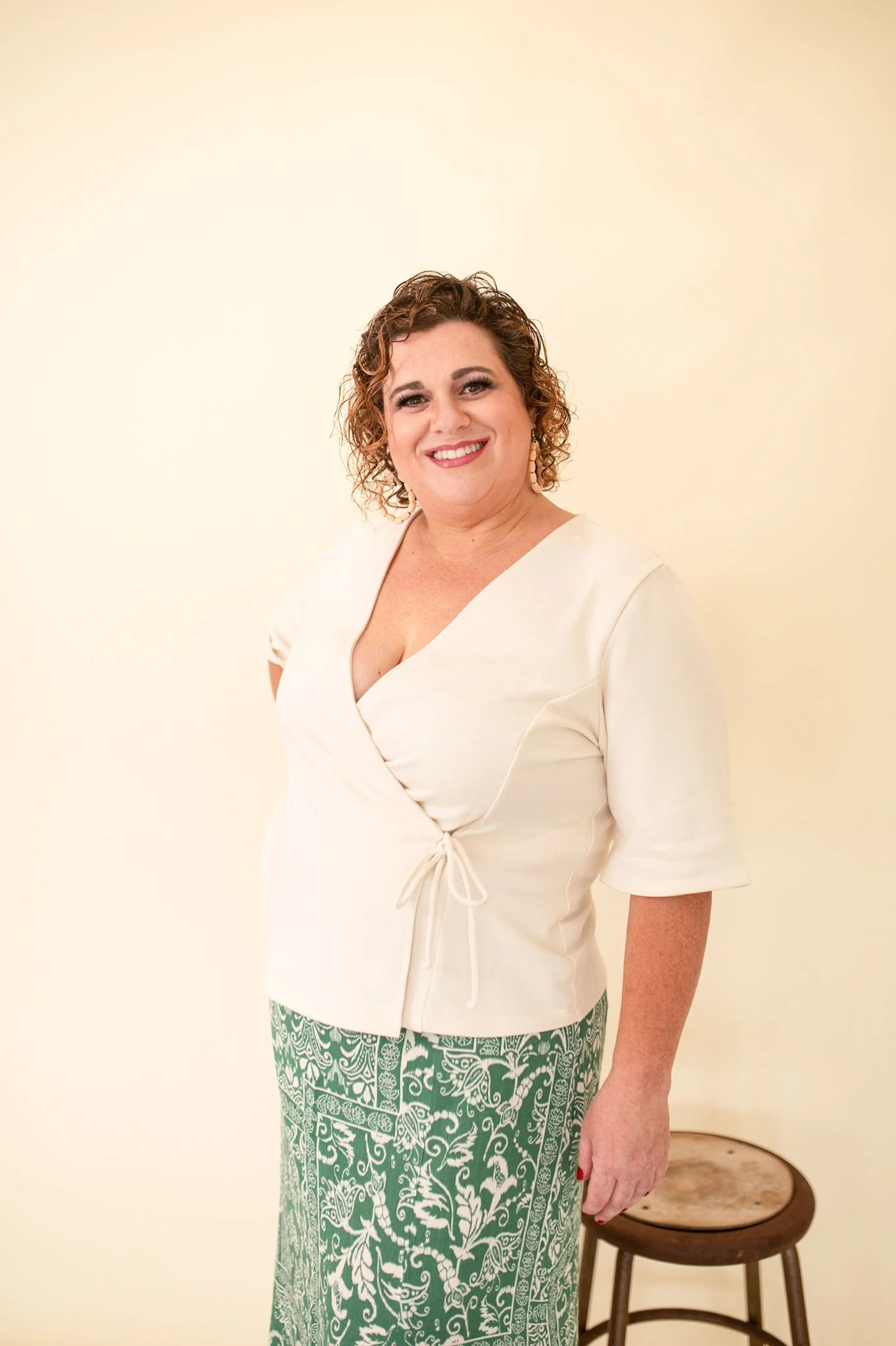 Cream wrap-style top with a V-neckline and waist tie detail.