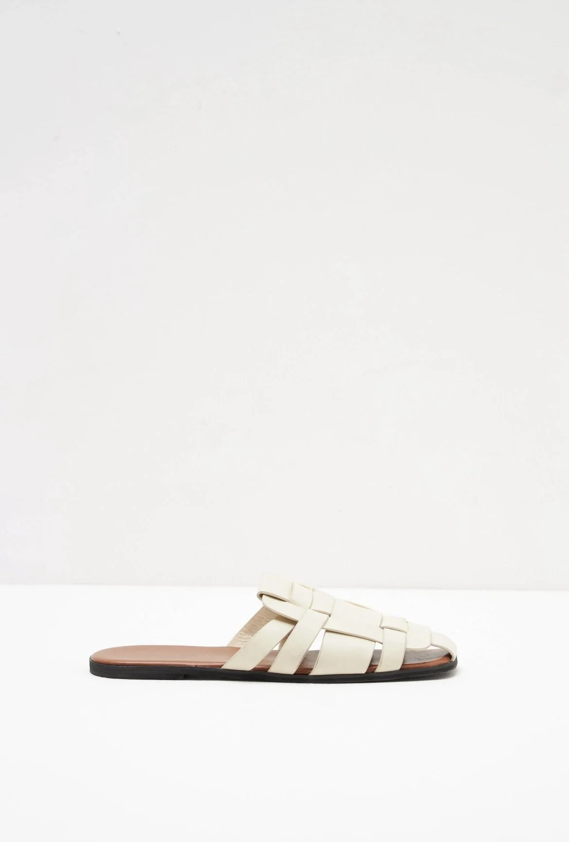 Cream woven flat mules with an open-toe design.