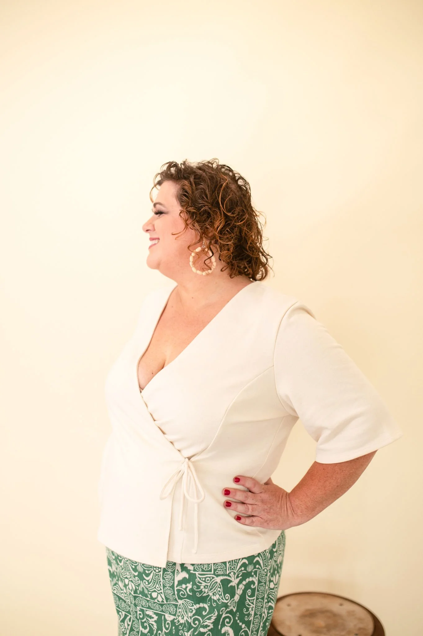 Cream wrap-style top with a V-neckline and waist tie detail.