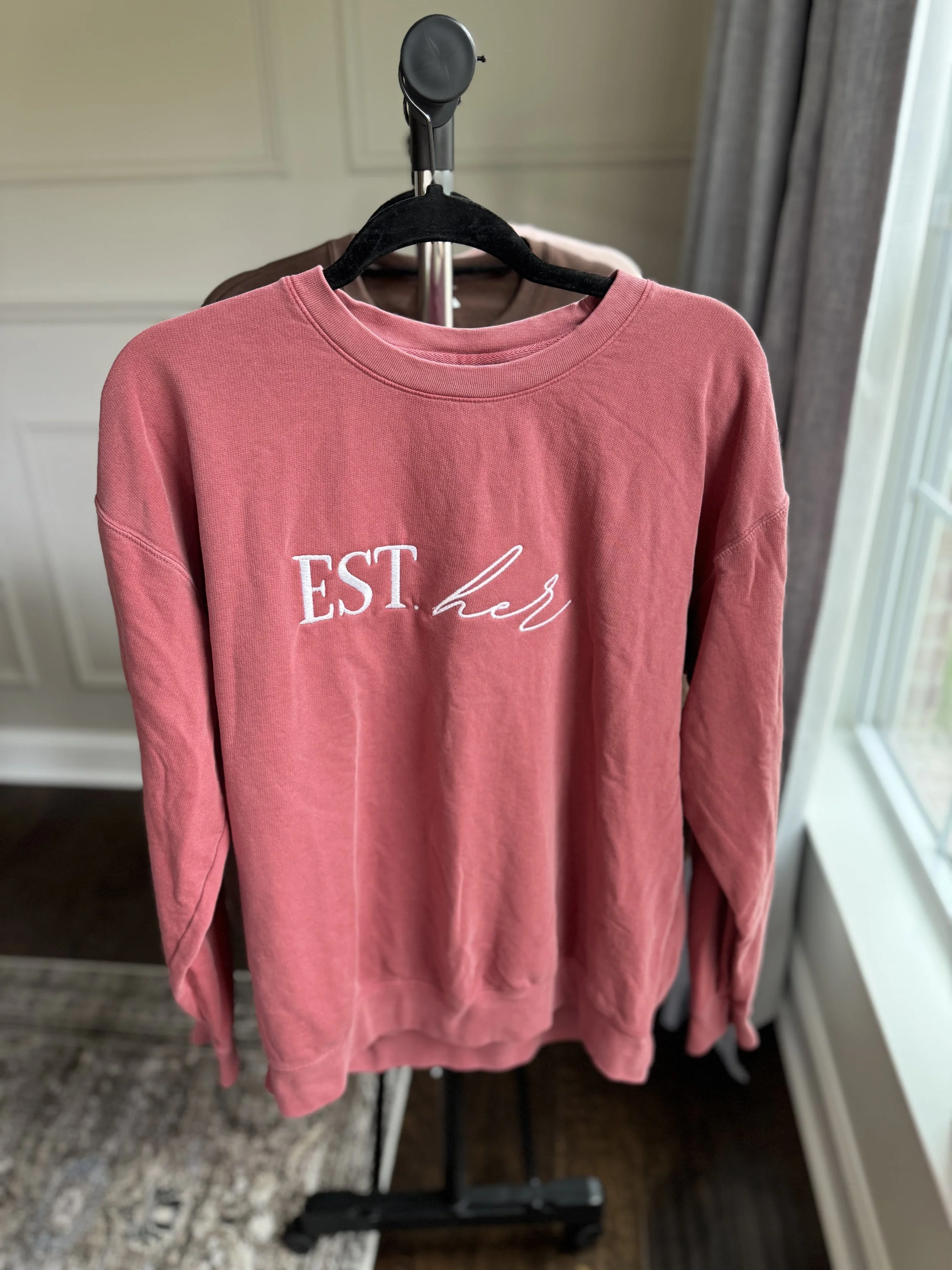 Dusty rose sweatshirt with Esther logo graphic.