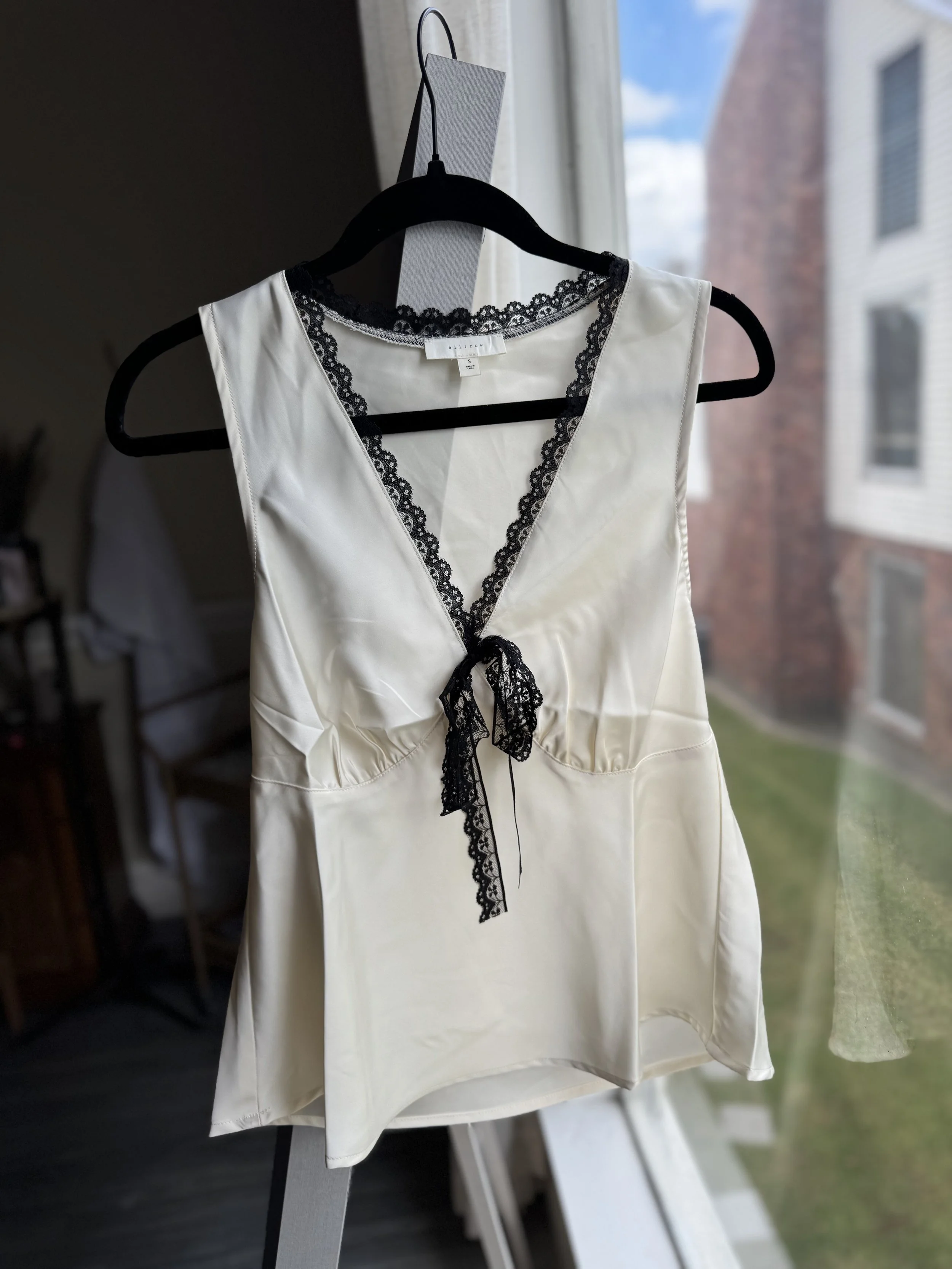 Sleeveless cream top with contrast trim and front tie detail.