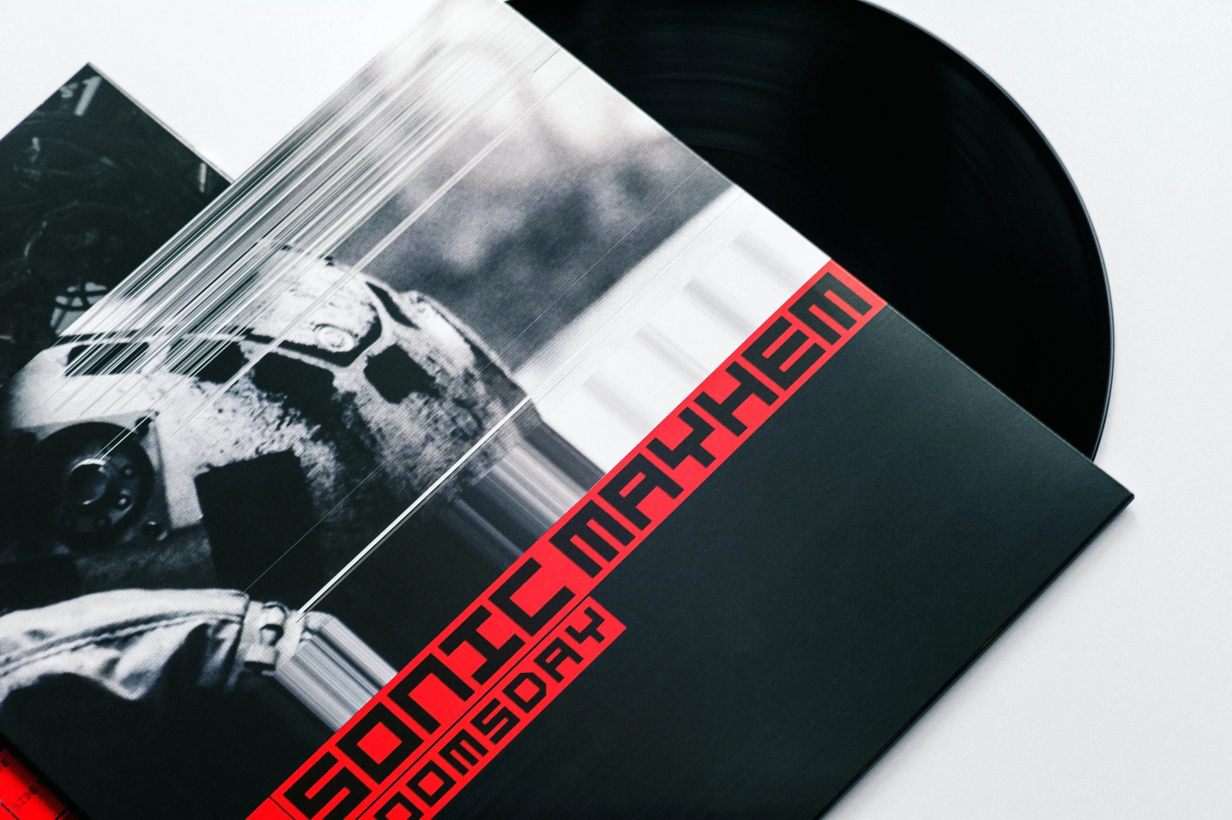 Close-up of a vinyl record and its album cover featuring a black and white photo of a person in a spacesuit, with red and black abstract text on a black background.