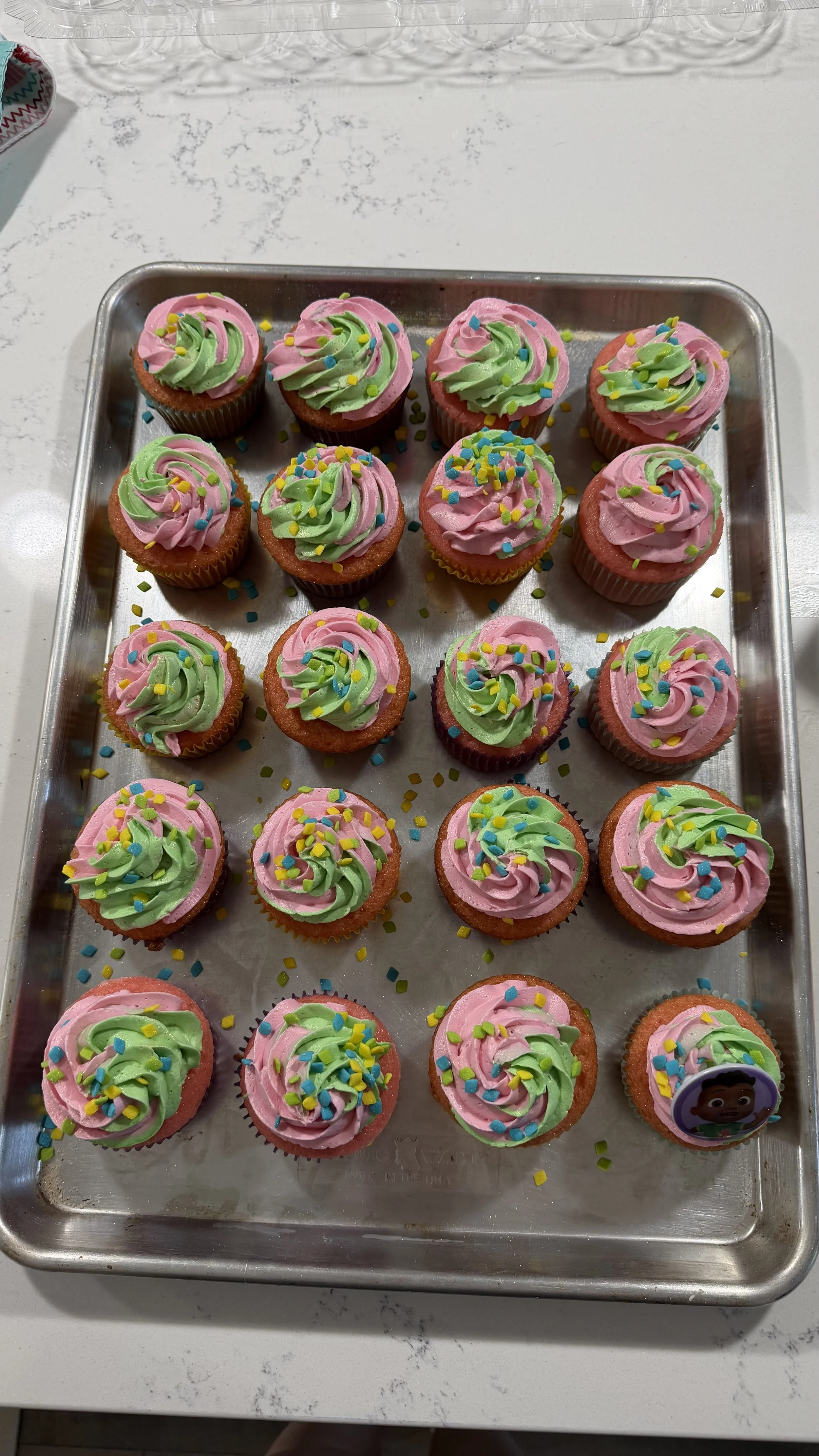 Custom children's birthday cupcakes, Cocomelon themed. 
Strawberry cupcake with pink/green american buttercream icing and assorted sprinkles.