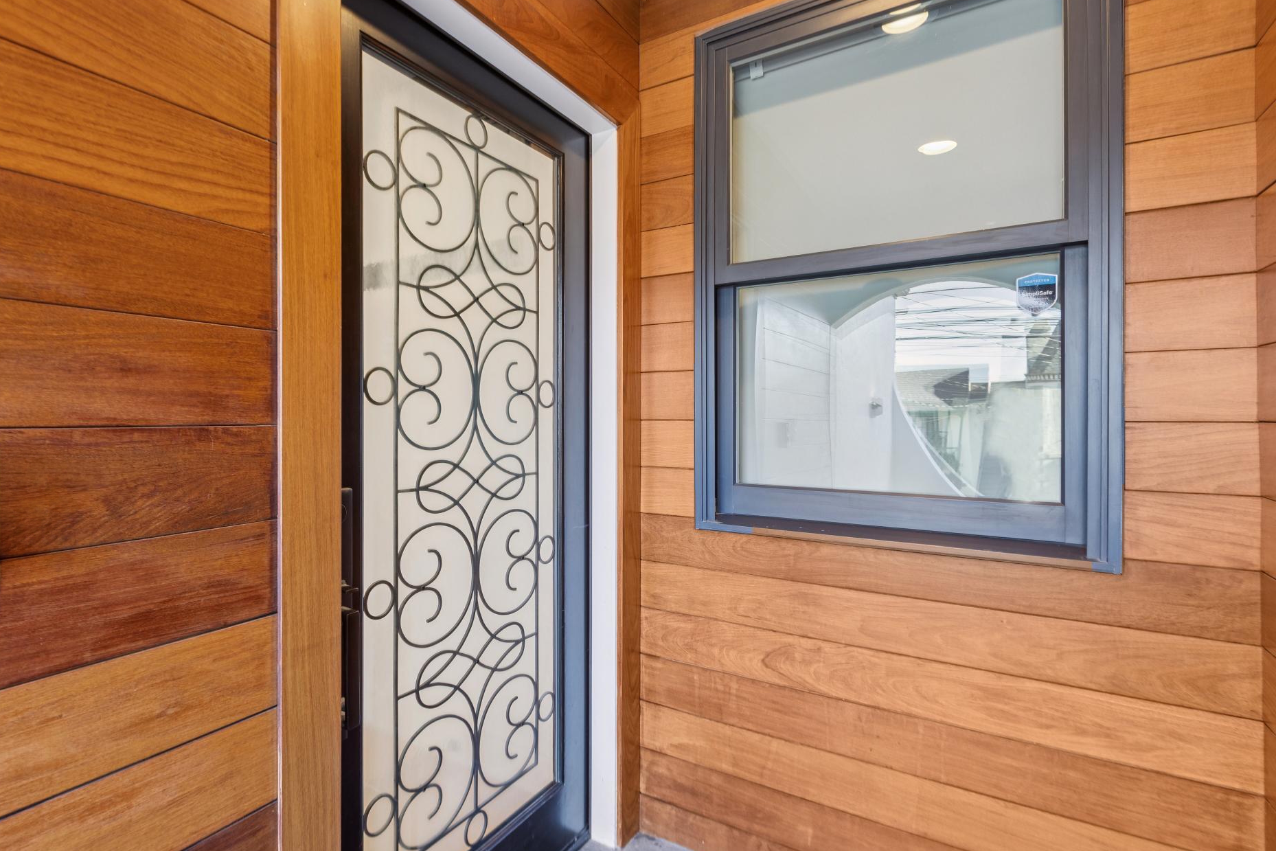Wooden house exterior with a decorative metal door and a window.