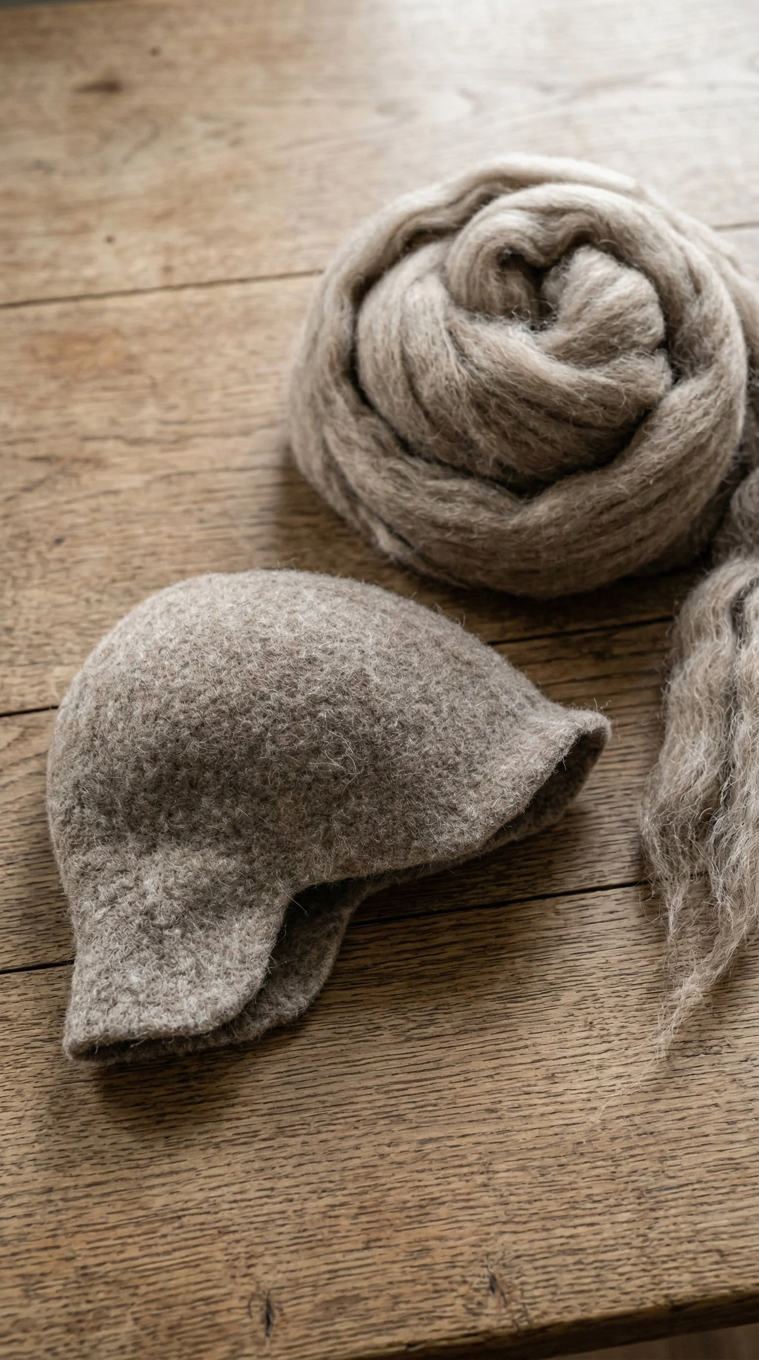 Felted_hat_laying_on_a_table_with_wool_roving_prod_delpmaspu.png