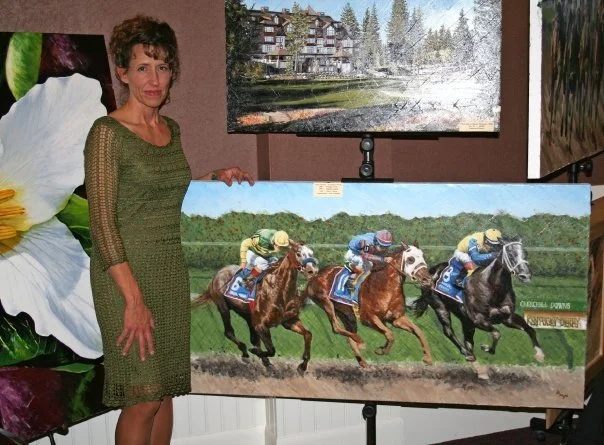 A woman in a green dress standing next to a painting of a horse race with four jockeys riding horses on a track.