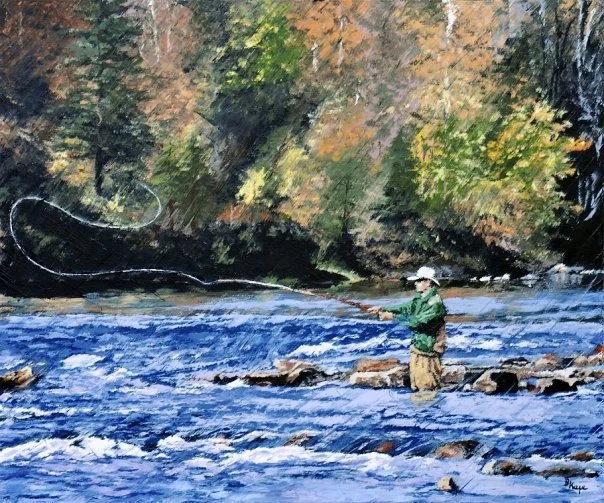 Person fishing in a river with rocks, surrounded by trees with fall foliage.
