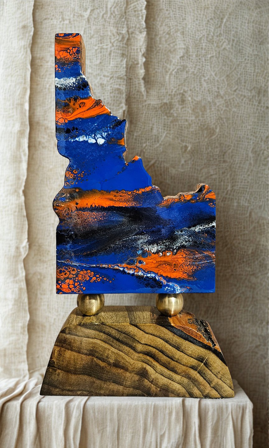 Abstract painted sculpture with blue, orange, black, and white colors on a wooden base.